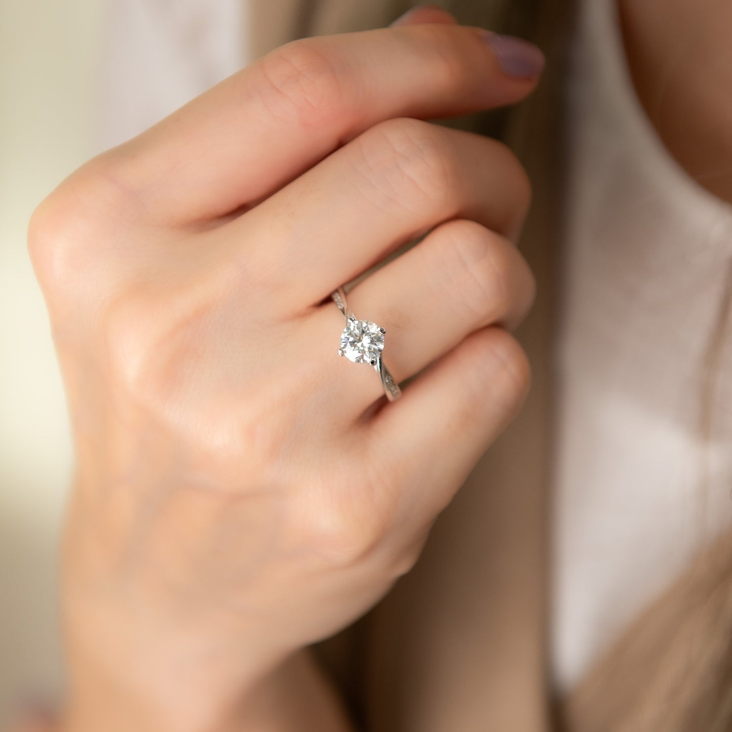 Close-up of a hand wearing a diamond ring with a soft background