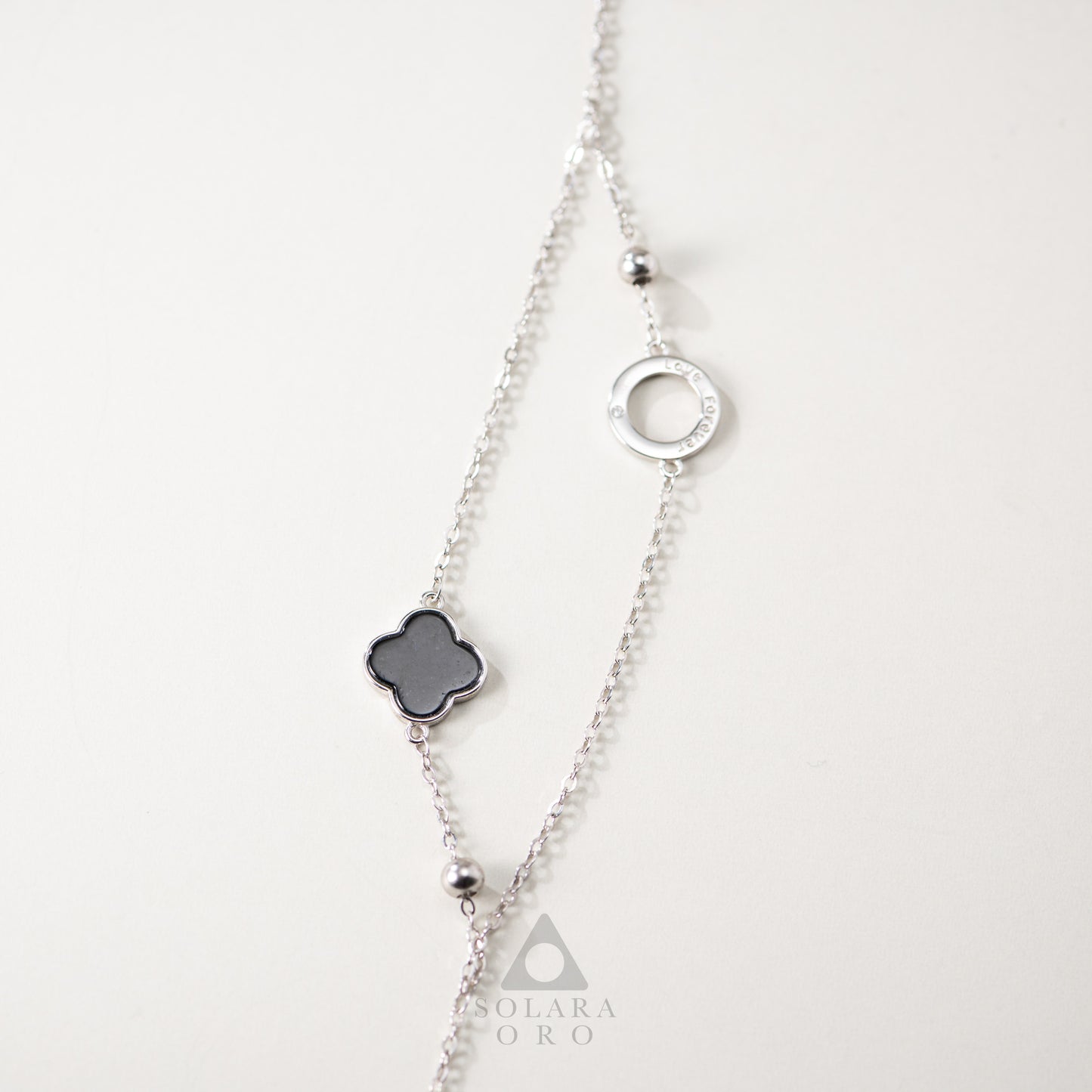 Silver necklace with a clover-shaped pendant on a white background
