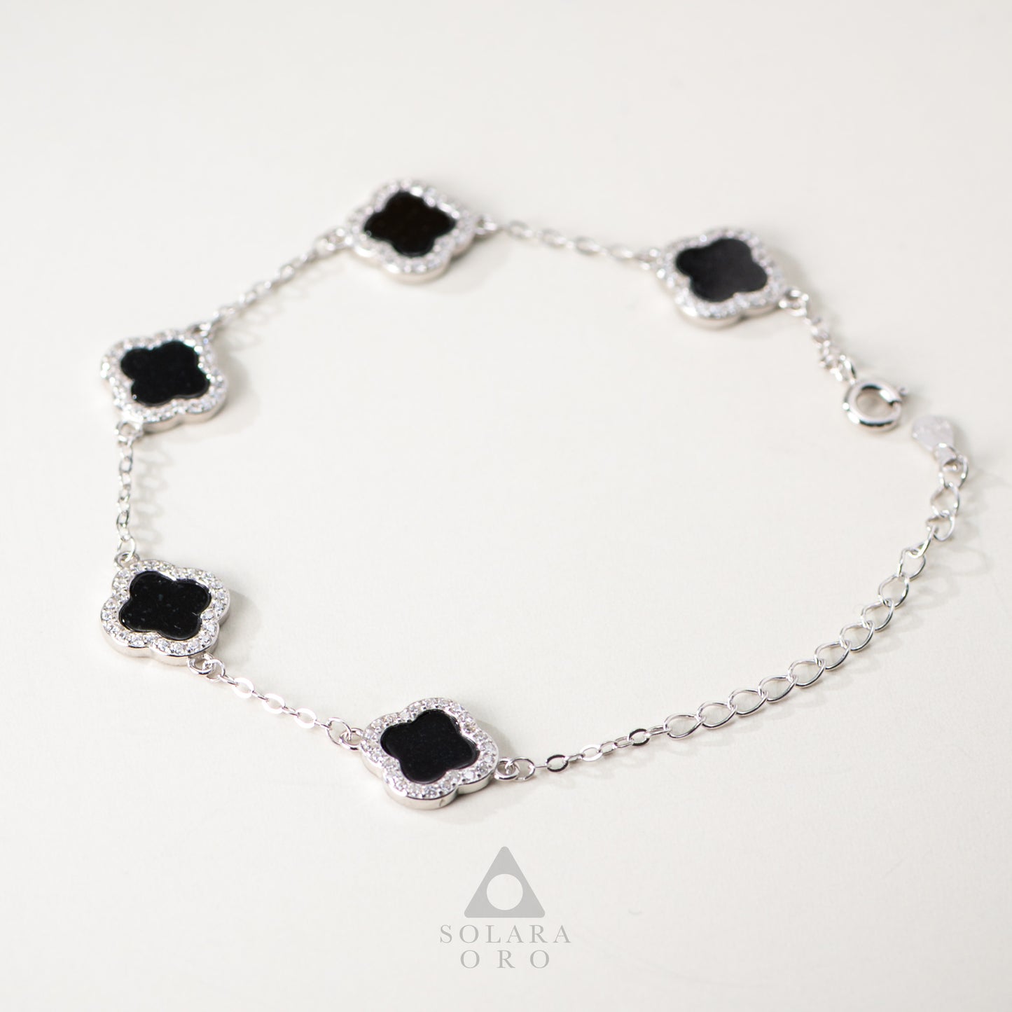 Silver bracelet with black clover-shaped stones on a white background, featuring the brand 'Solara Oro'.