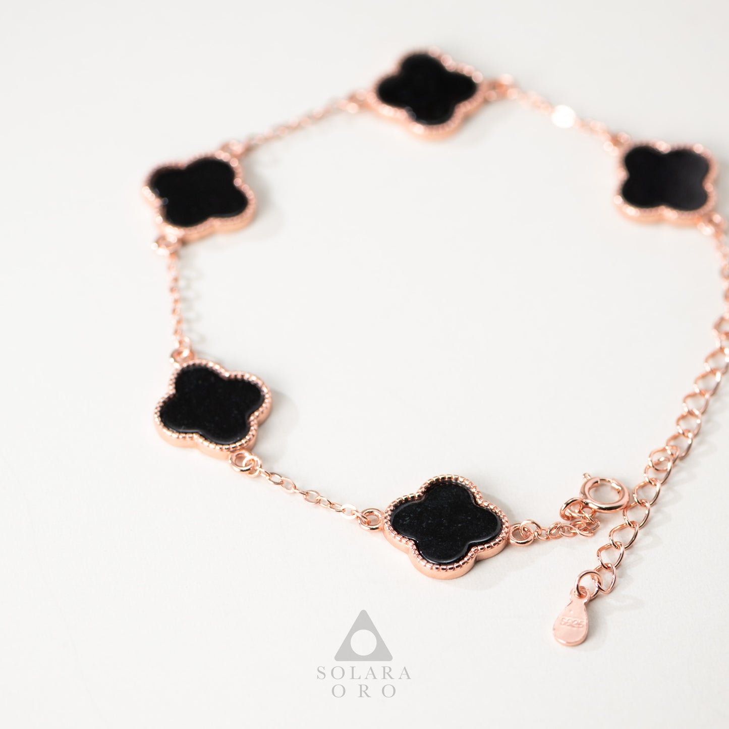 Rose gold bracelet with black clover-shaped charms on a white background, featuring the brand 'Solara Oro'.