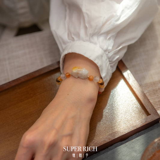 Close-up of a wrist wearing a beaded bracelet on a wooden surface with 'SUPER RICH' branding.