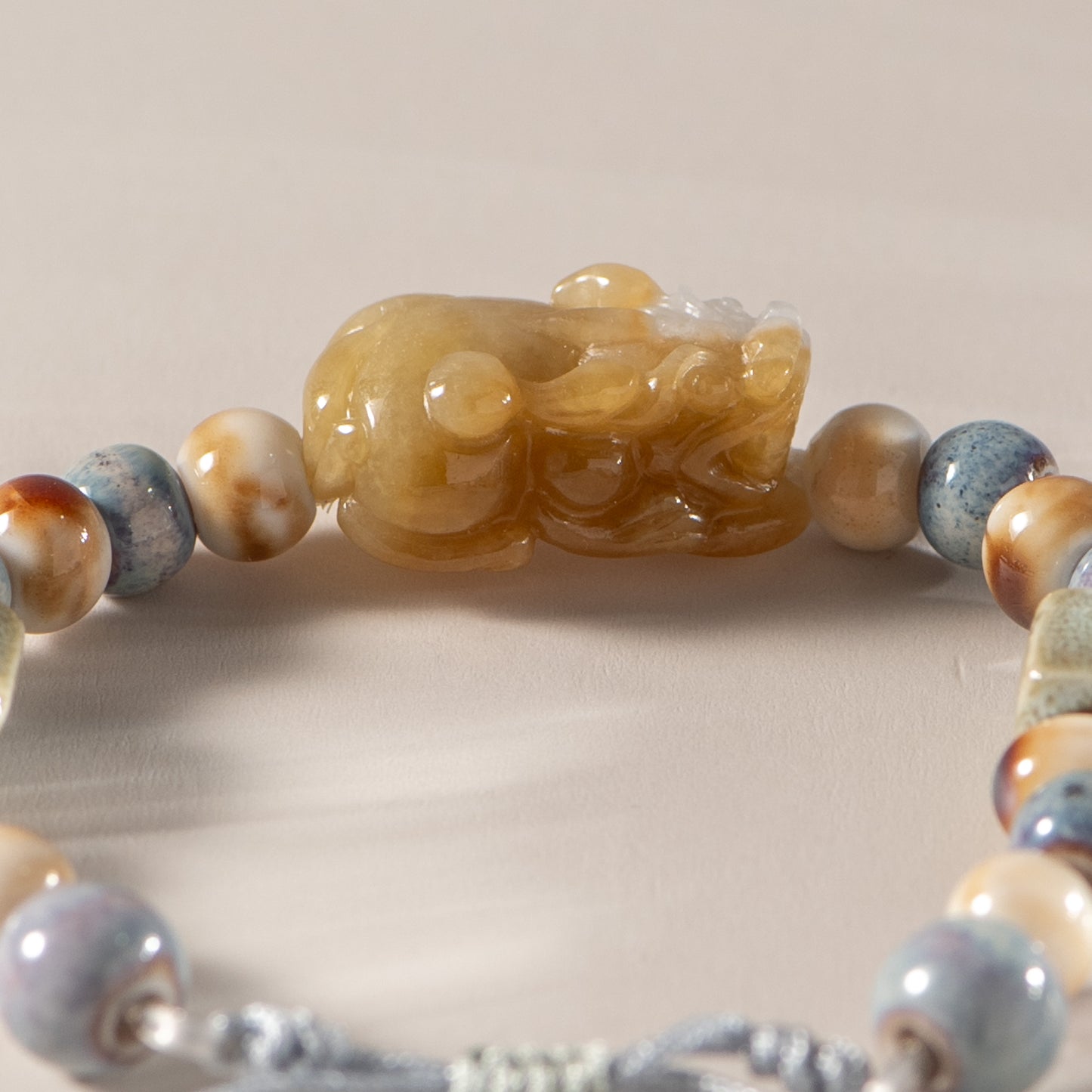 Bracelet with marbled beads and a central carved stone piece on a neutral background