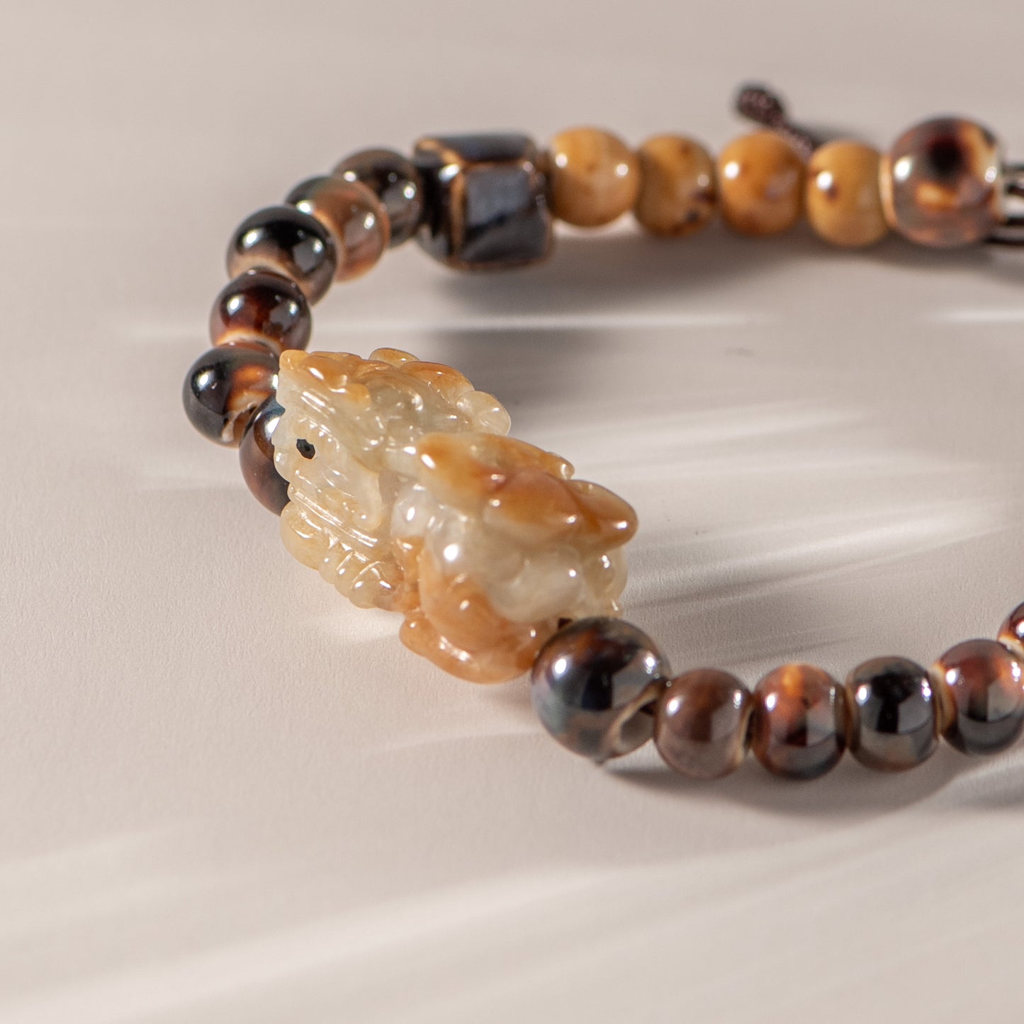Bracelet with tiger eye beads and a carved stone lion on a neutral background