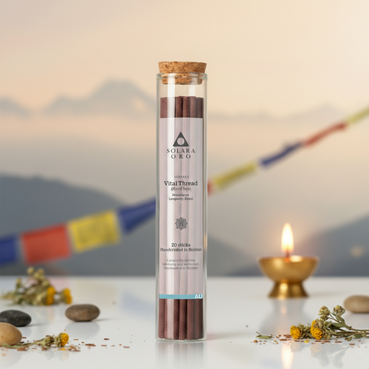 Tube of incense sticks with a blurred background featuring a candle and prayer flags.