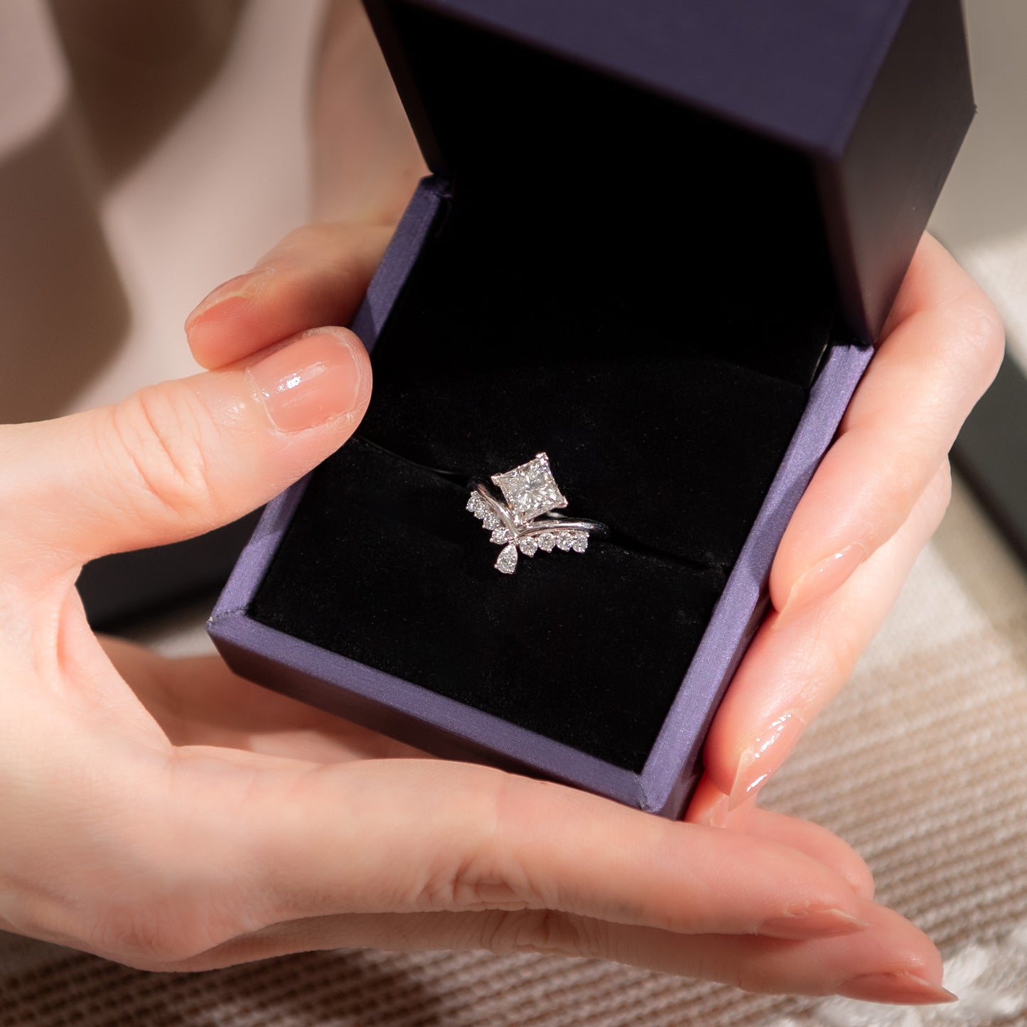 Butterfly-shaped diamond ring in a purple box held by hands