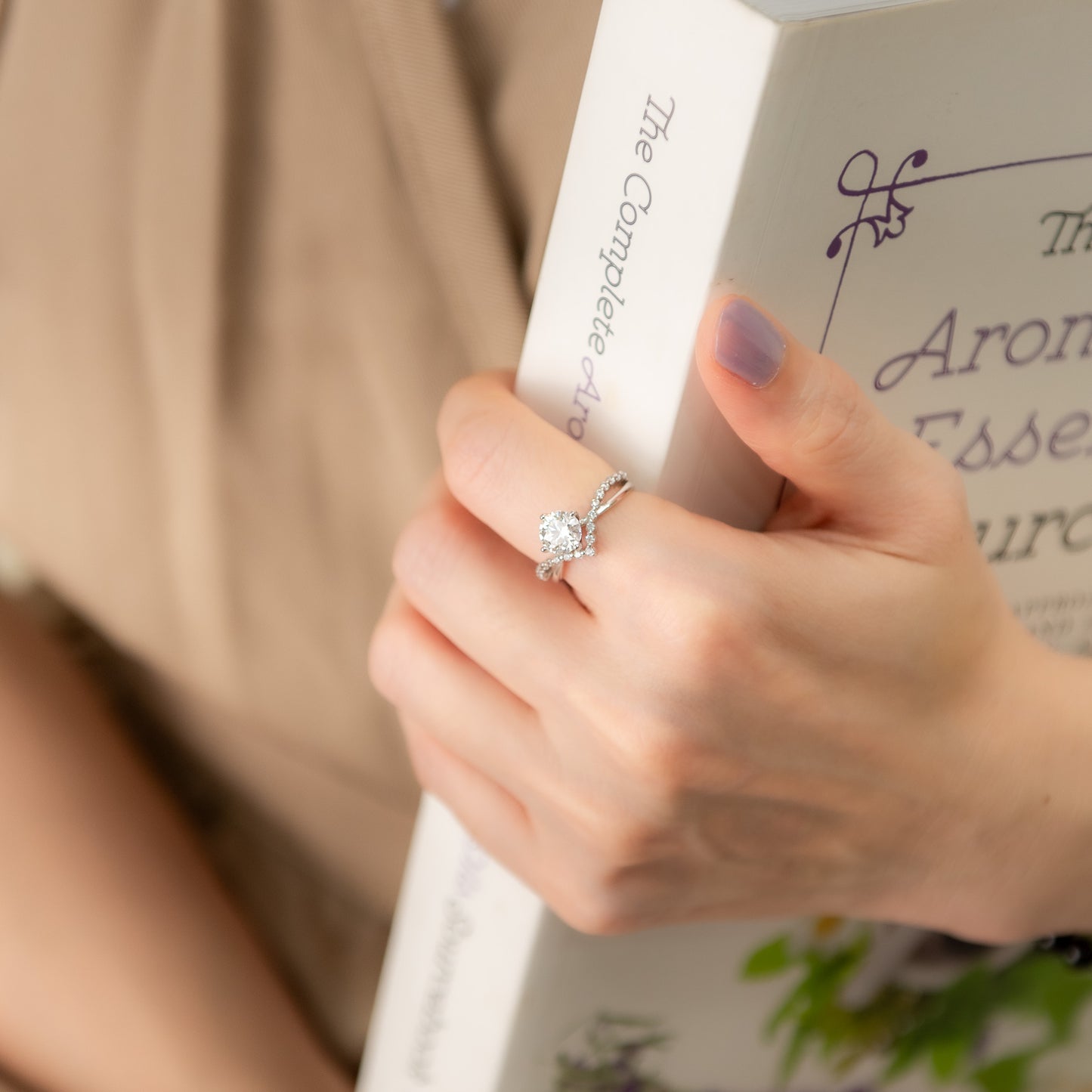 Hand holding a ring with a blurred book in the background