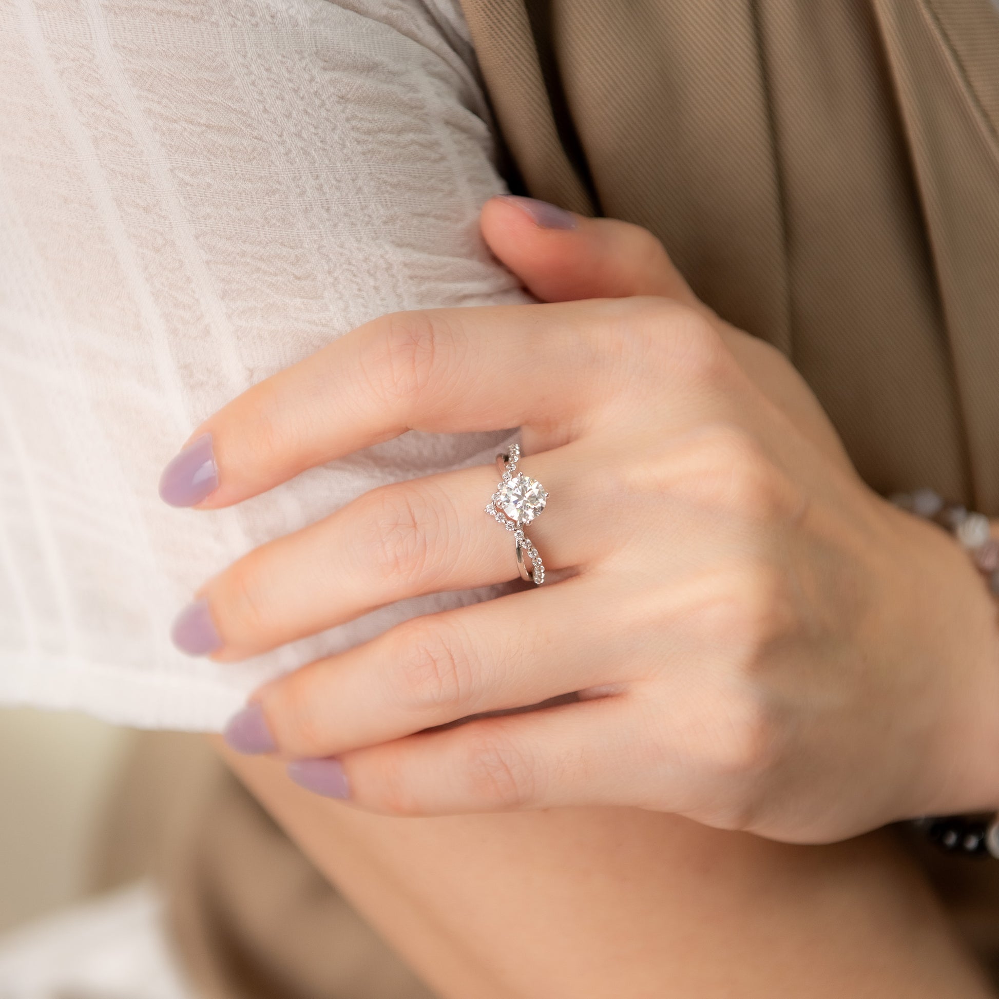 Close-up of a hand wearing an engagement ring with a blurred background