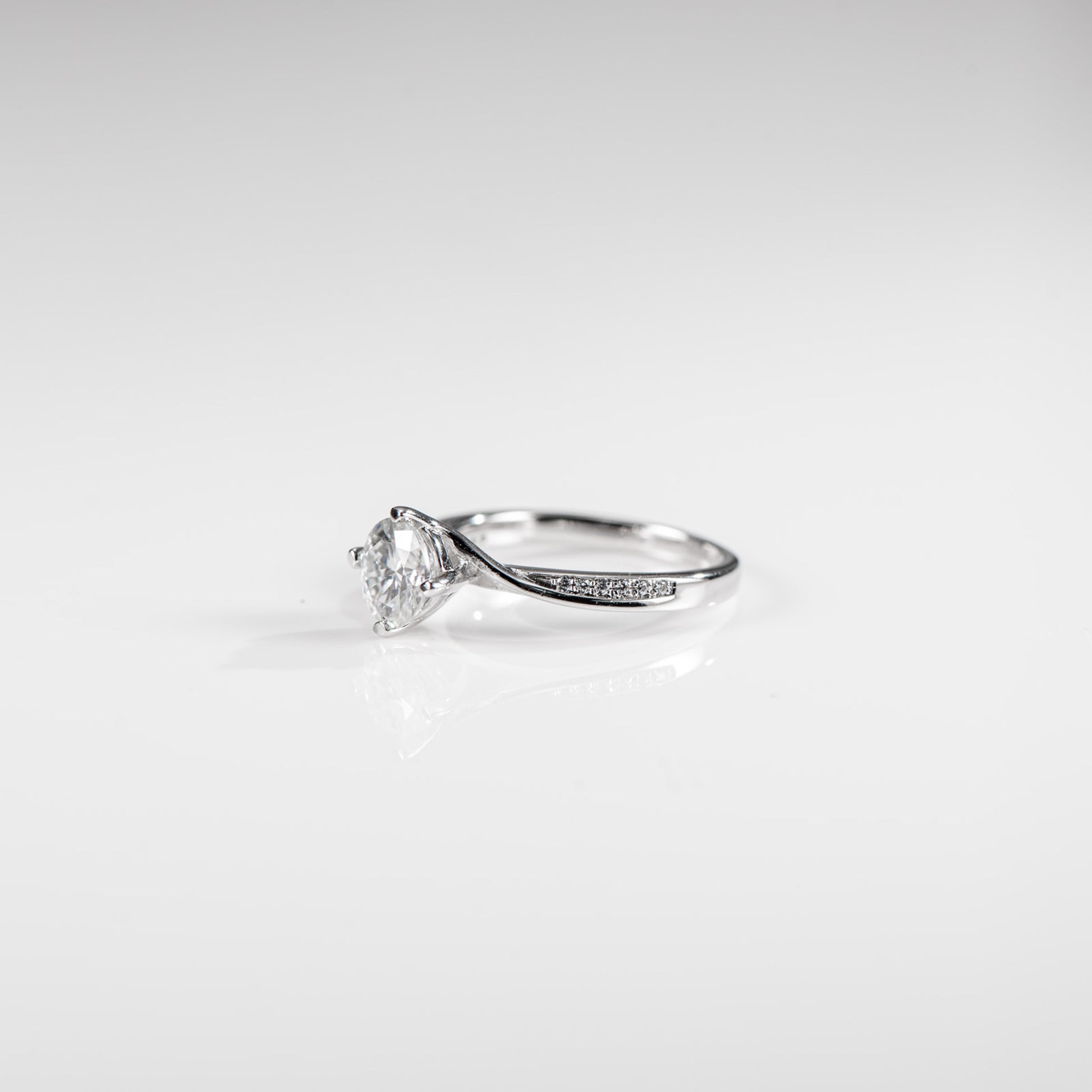 Silver ring with a diamond on a light gray background