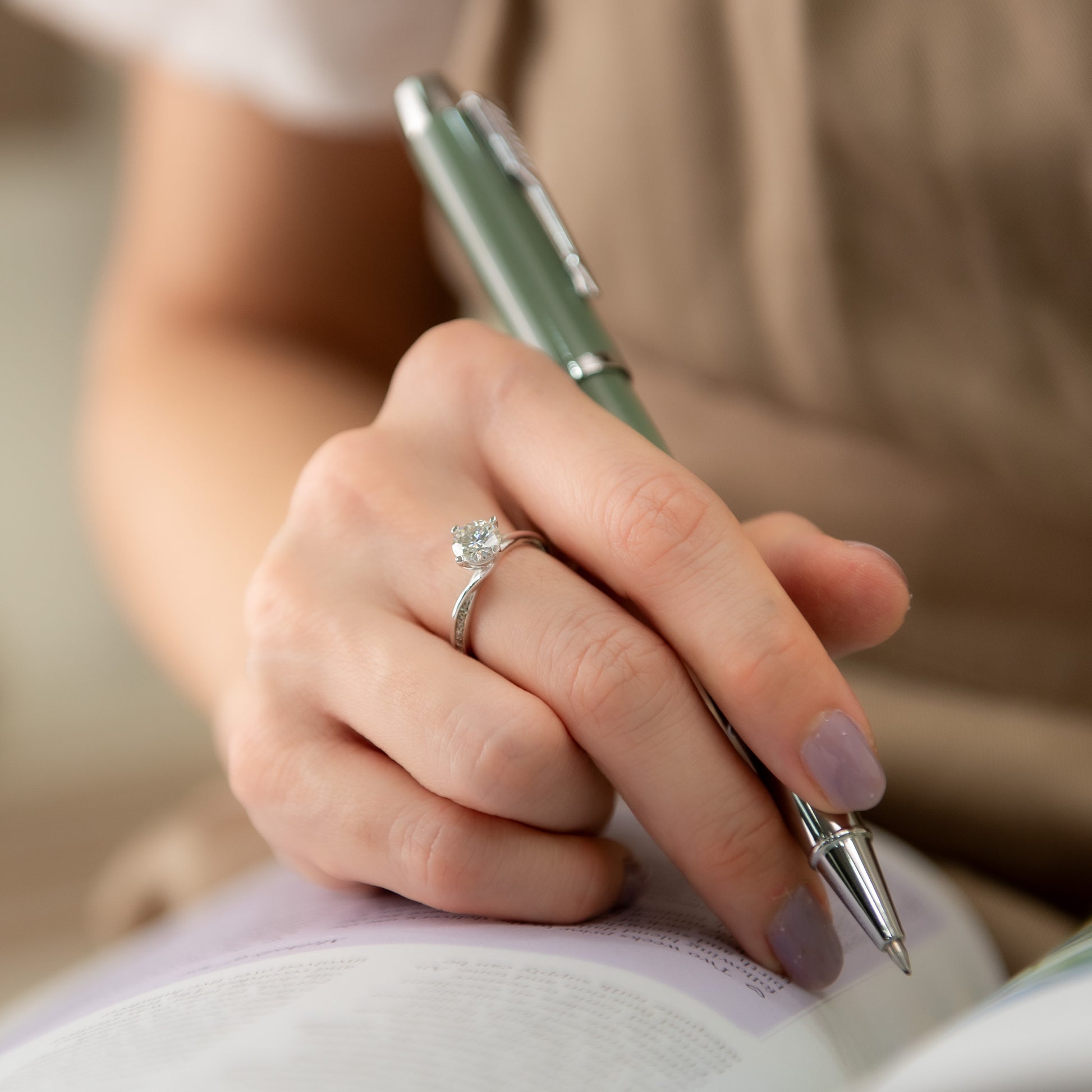 Hand holding a pen with a ring on a blurred background