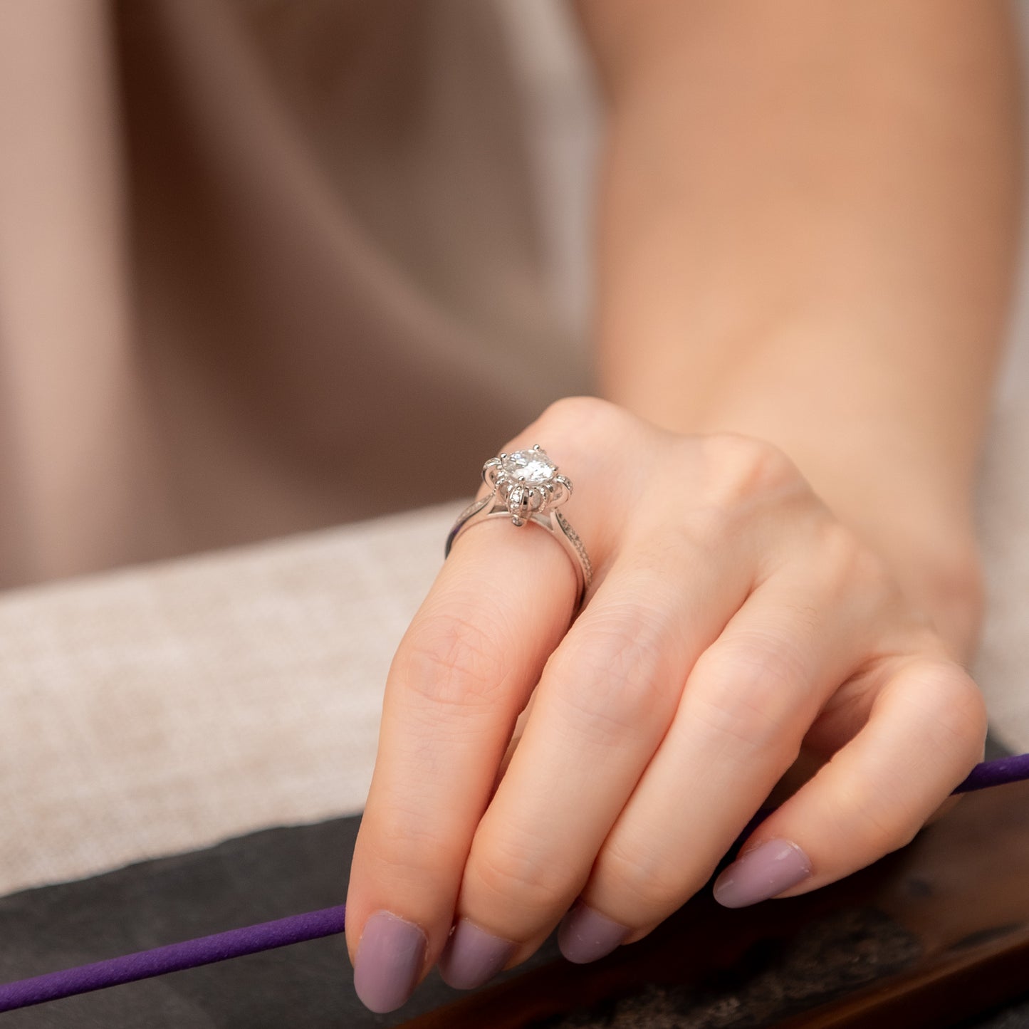Close-up of a hand wearing an engagement ring with a blurred background