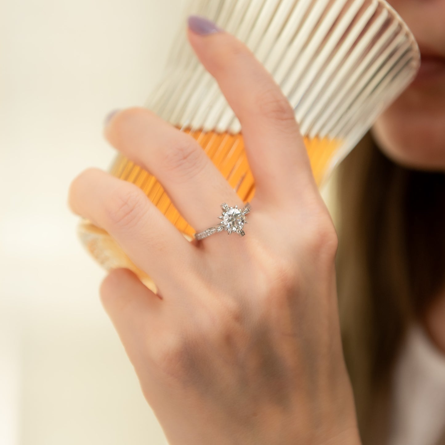 Hand holding a cup with a diamond ring on a blurred background