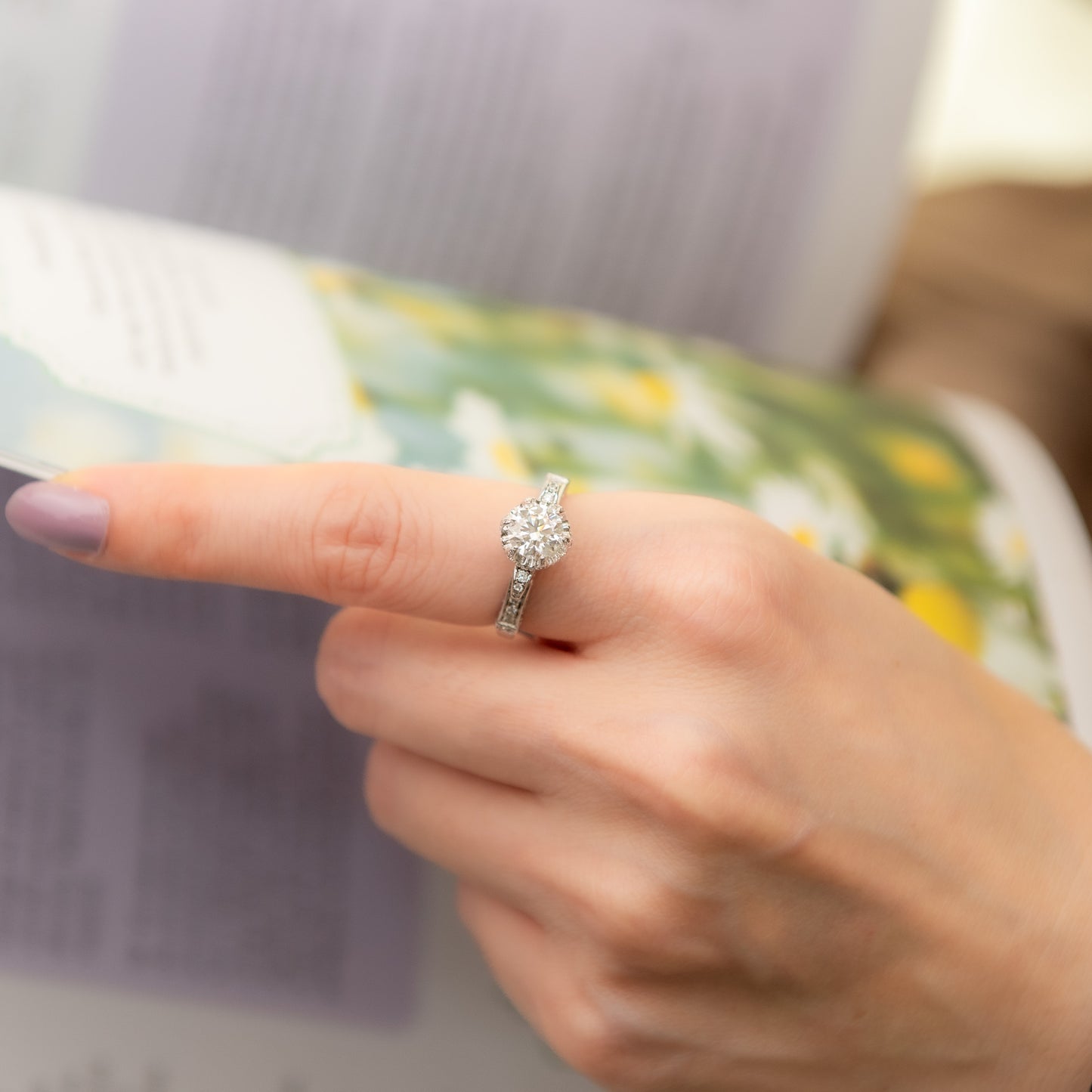 Close-up of a hand wearing a diamond ring with a blurred background