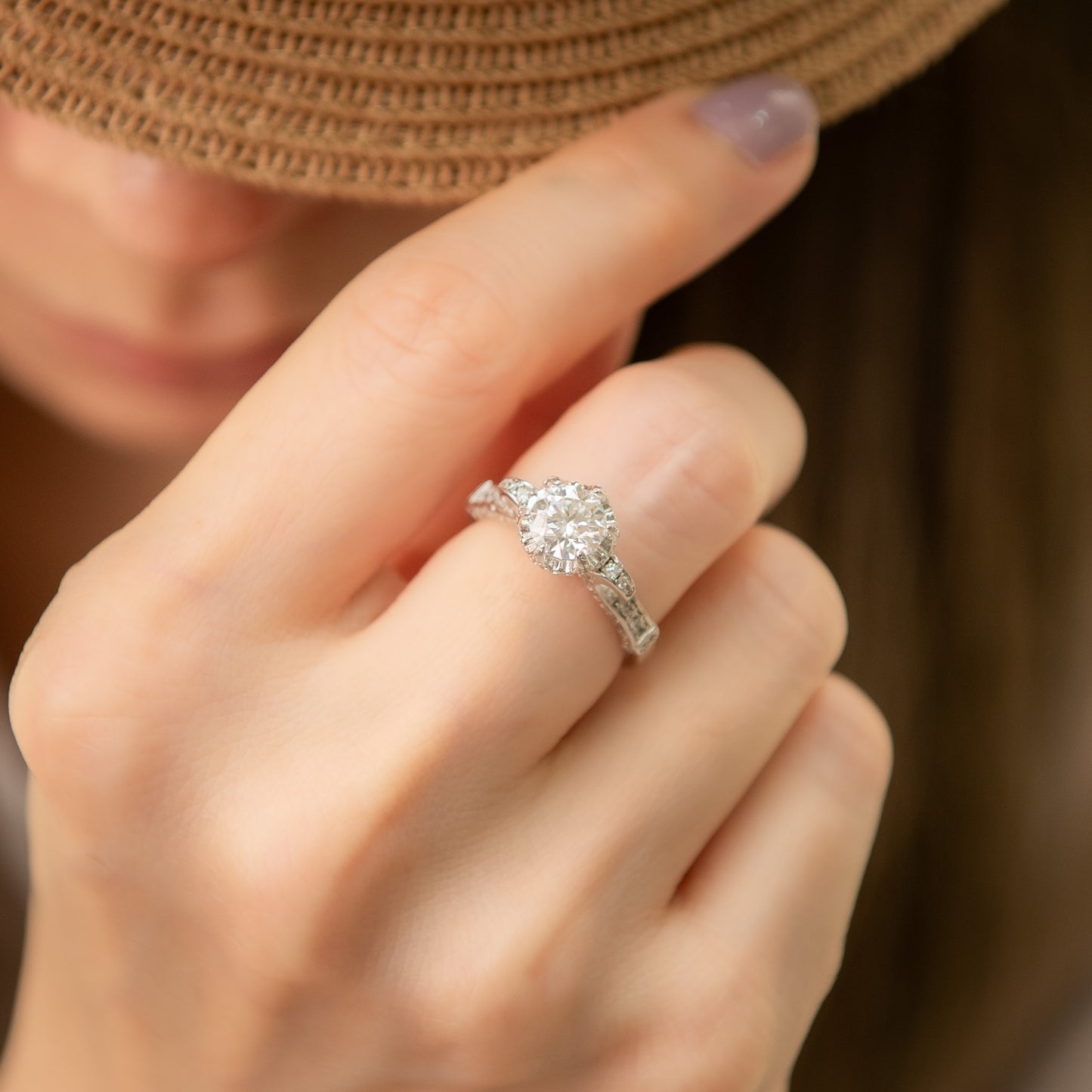 Close-up of a hand wearing a diamond ring with a blurred background