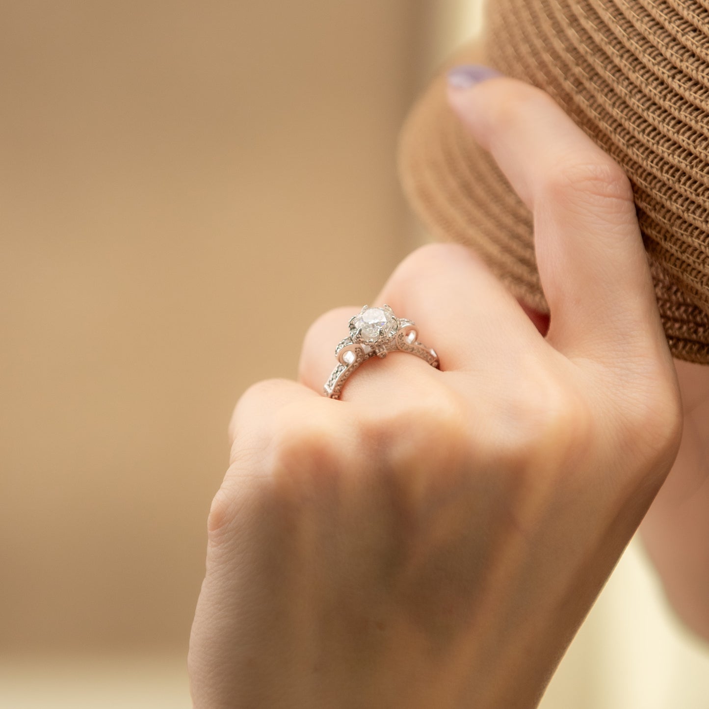 Close-up of a hand wearing a diamond ring with a blurred background