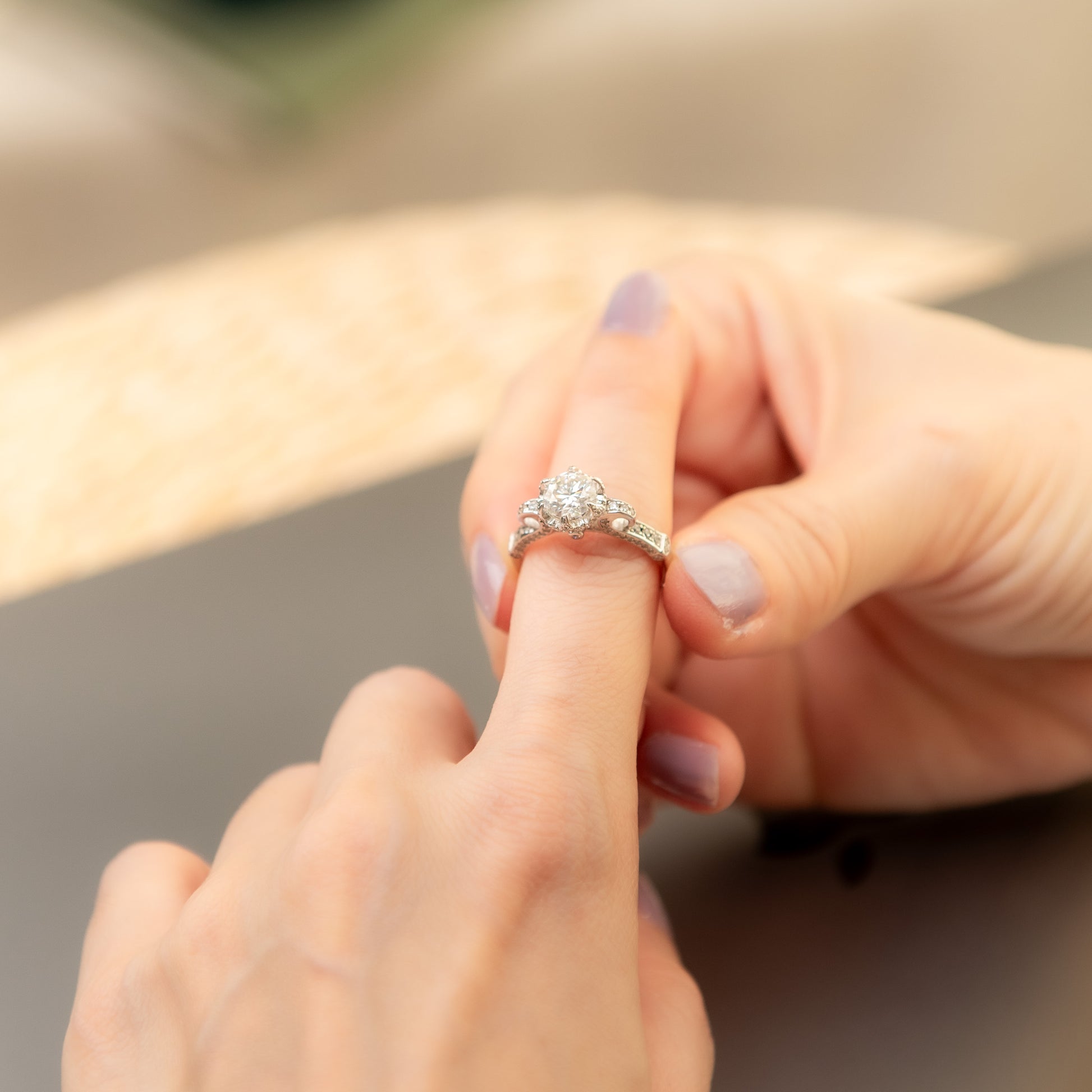 Close-up of a hand wearing a diamond ring with another hand touching the finger.