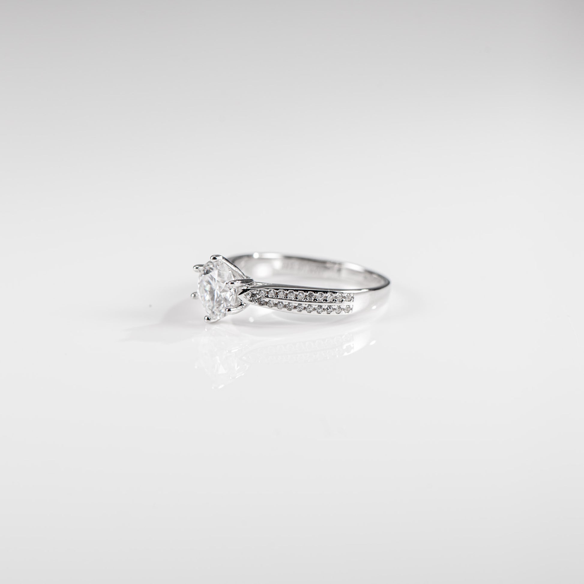 Silver ring with a diamond on a light gray background