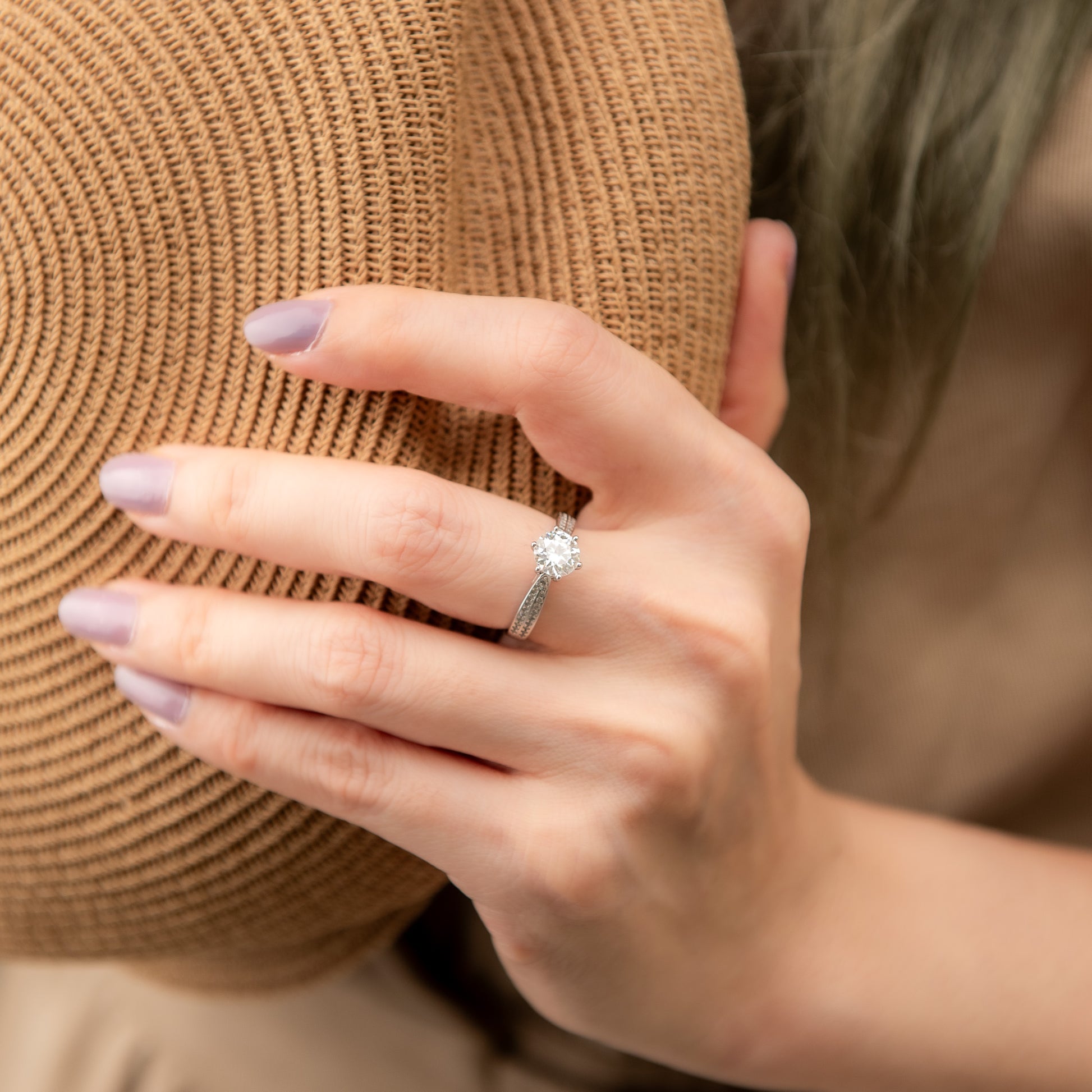 Hand wearing a diamond ring on a blurred background