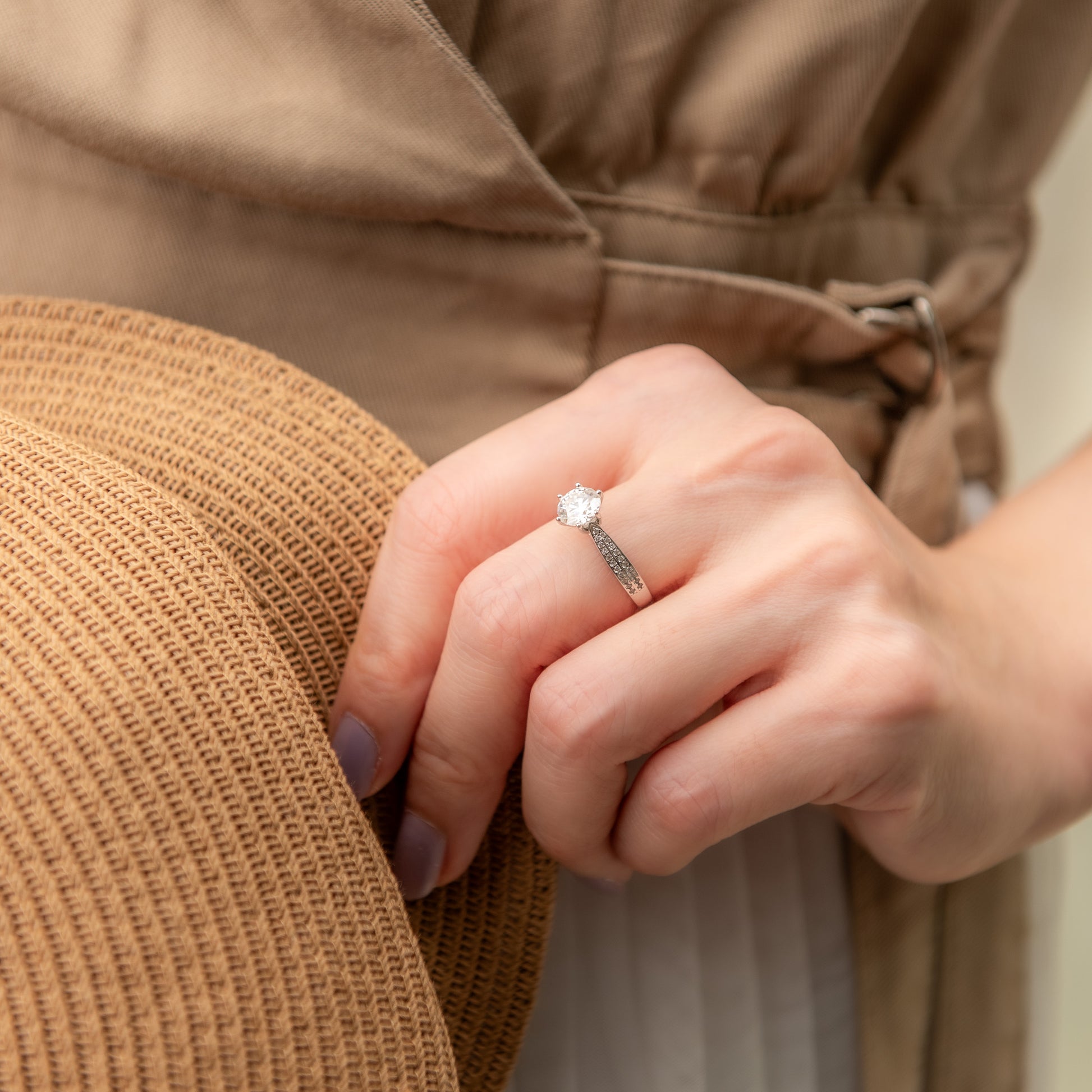 Close-up of a hand wearing a ring with a brown coat in the background