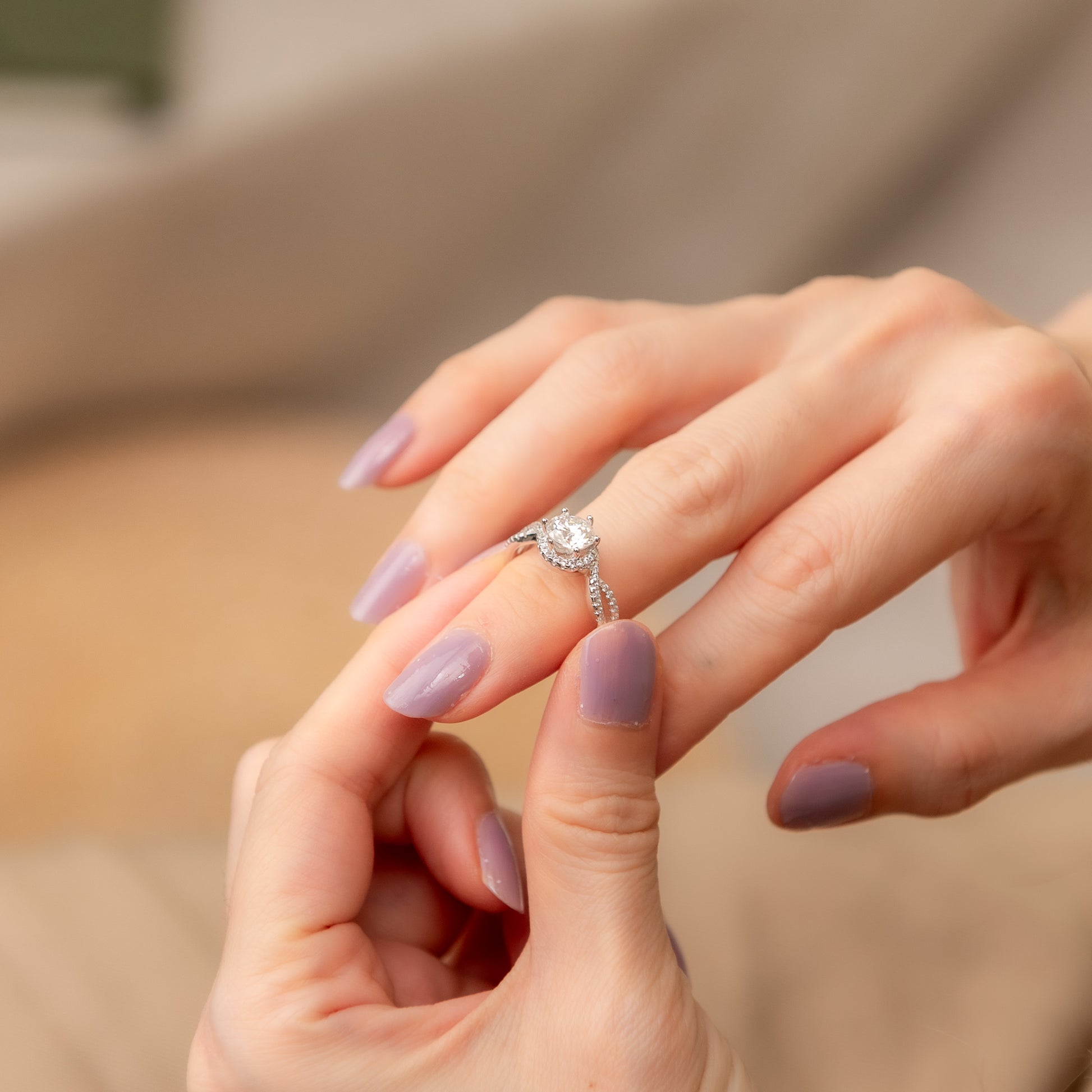 Close-up of a hand wearing an engagement ring with a blurred background