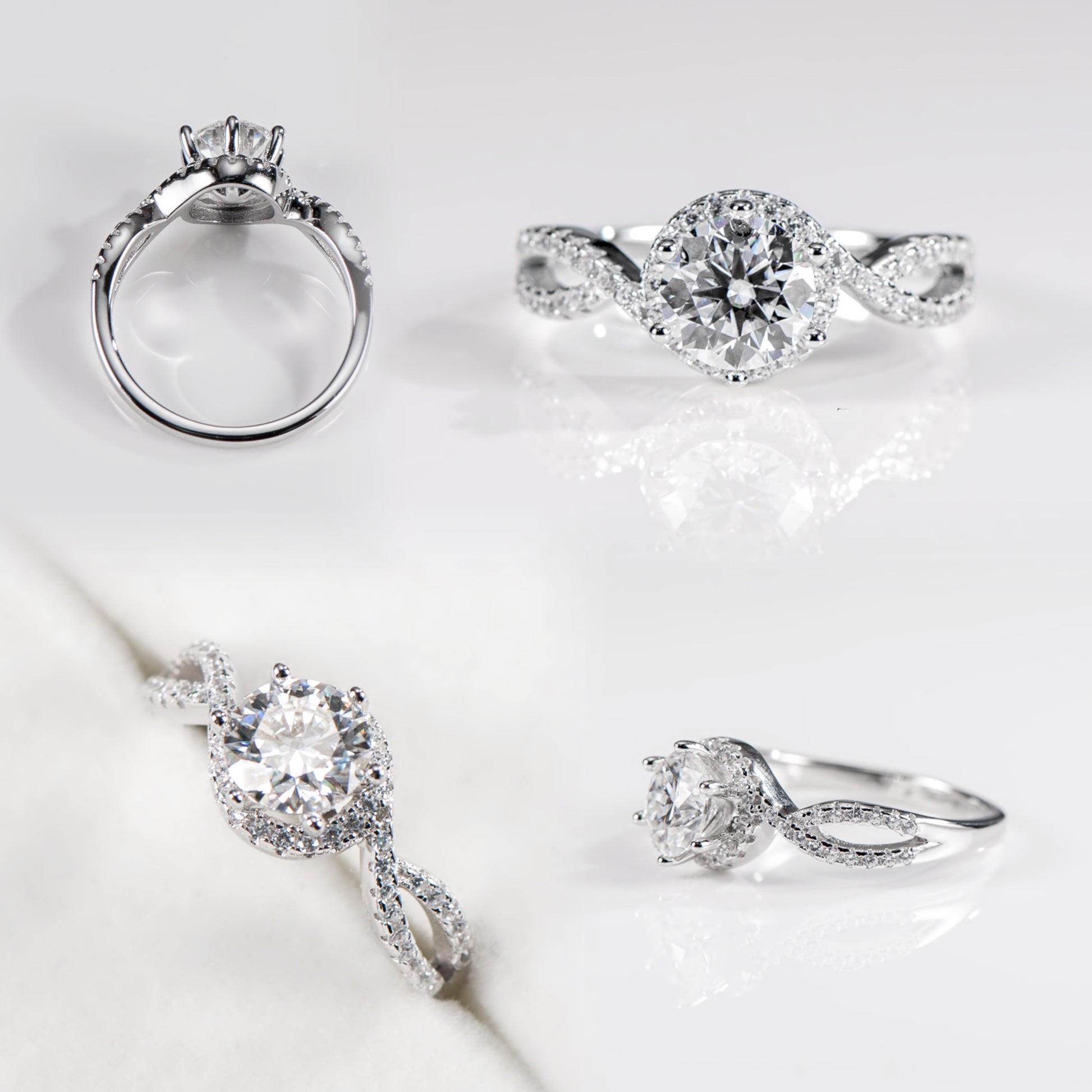 Four silver rings with diamond accents on a light gray background