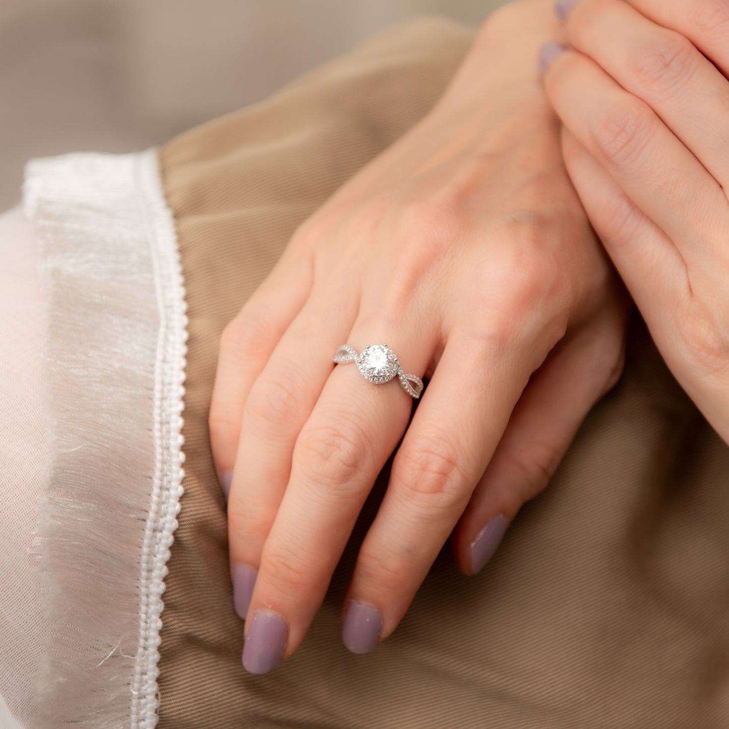 Close-up of a hand wearing a diamond ring with a neutral background