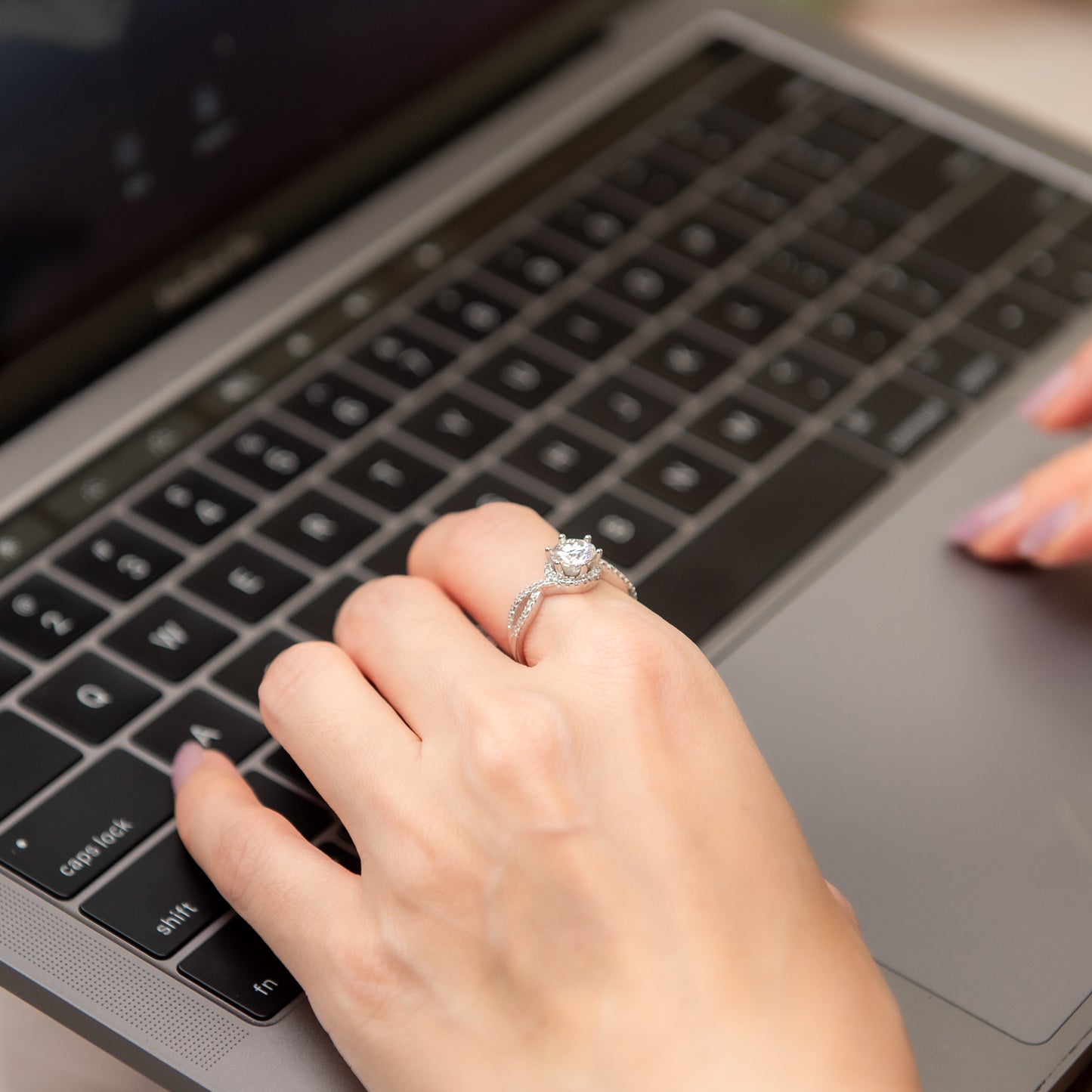 Hand with a ring on a laptop keyboard