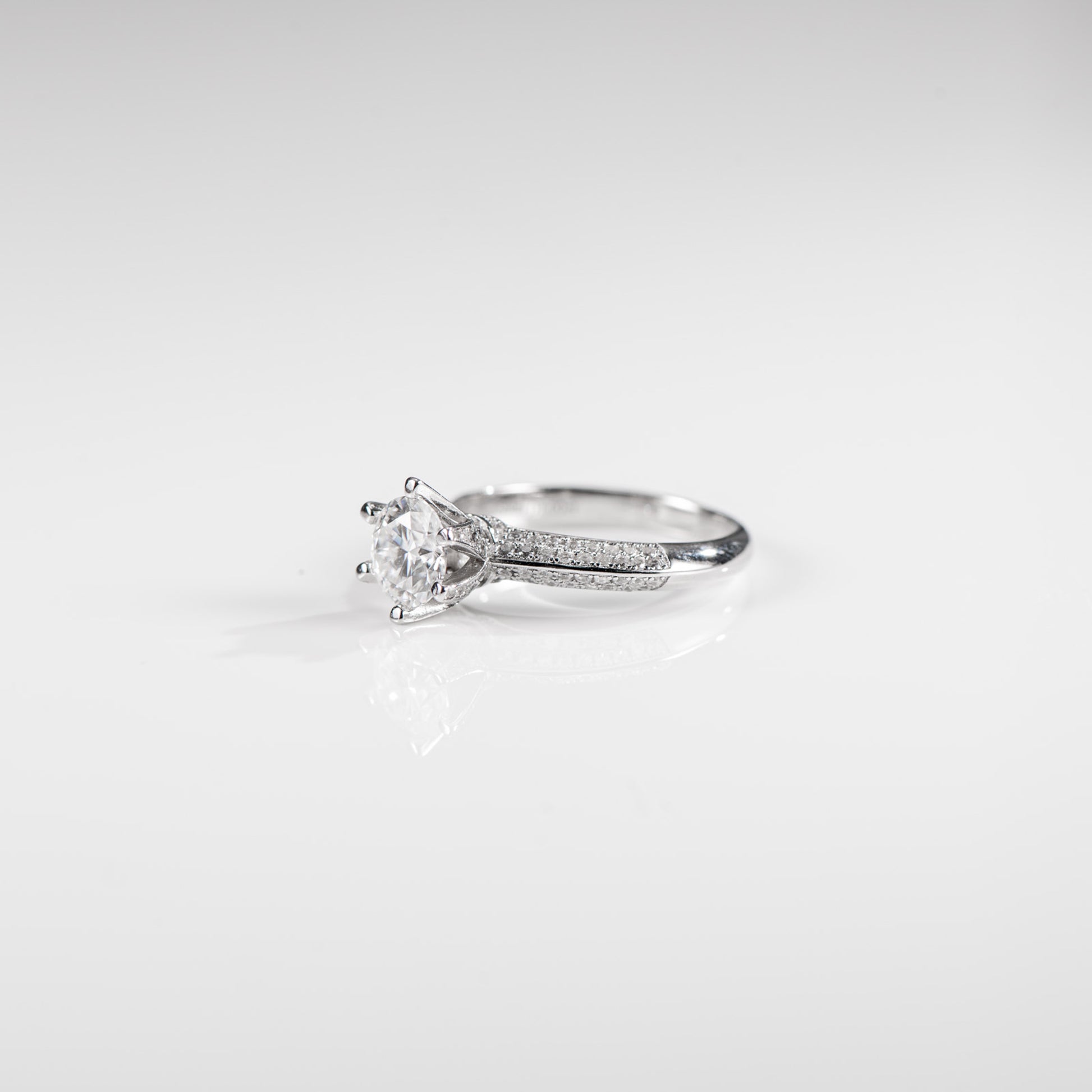 Silver ring with a diamond on a light gray background