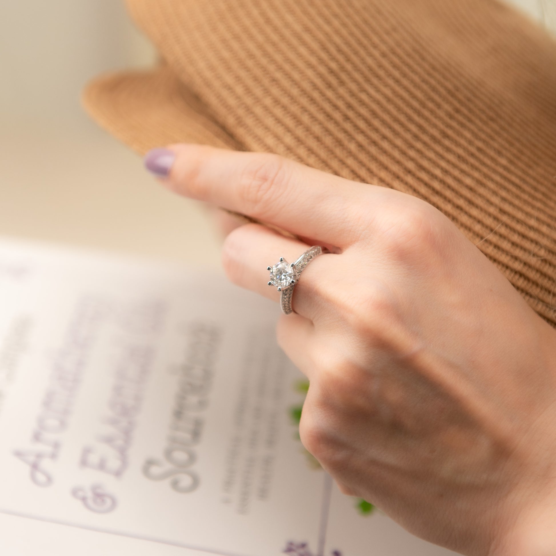 Hand wearing a diamond ring with a blurred background