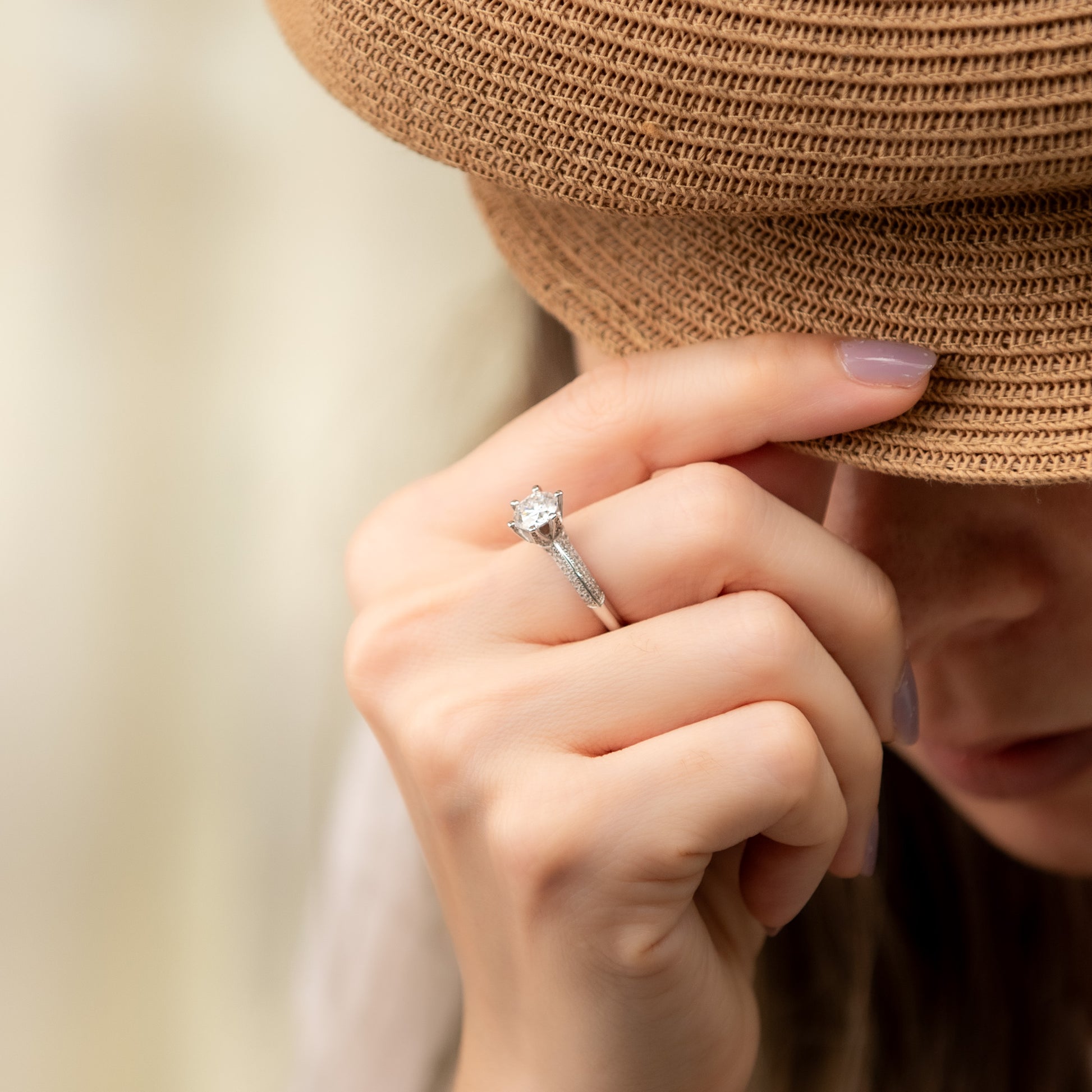 Close-up of a hand wearing a diamond ring with a blurred background