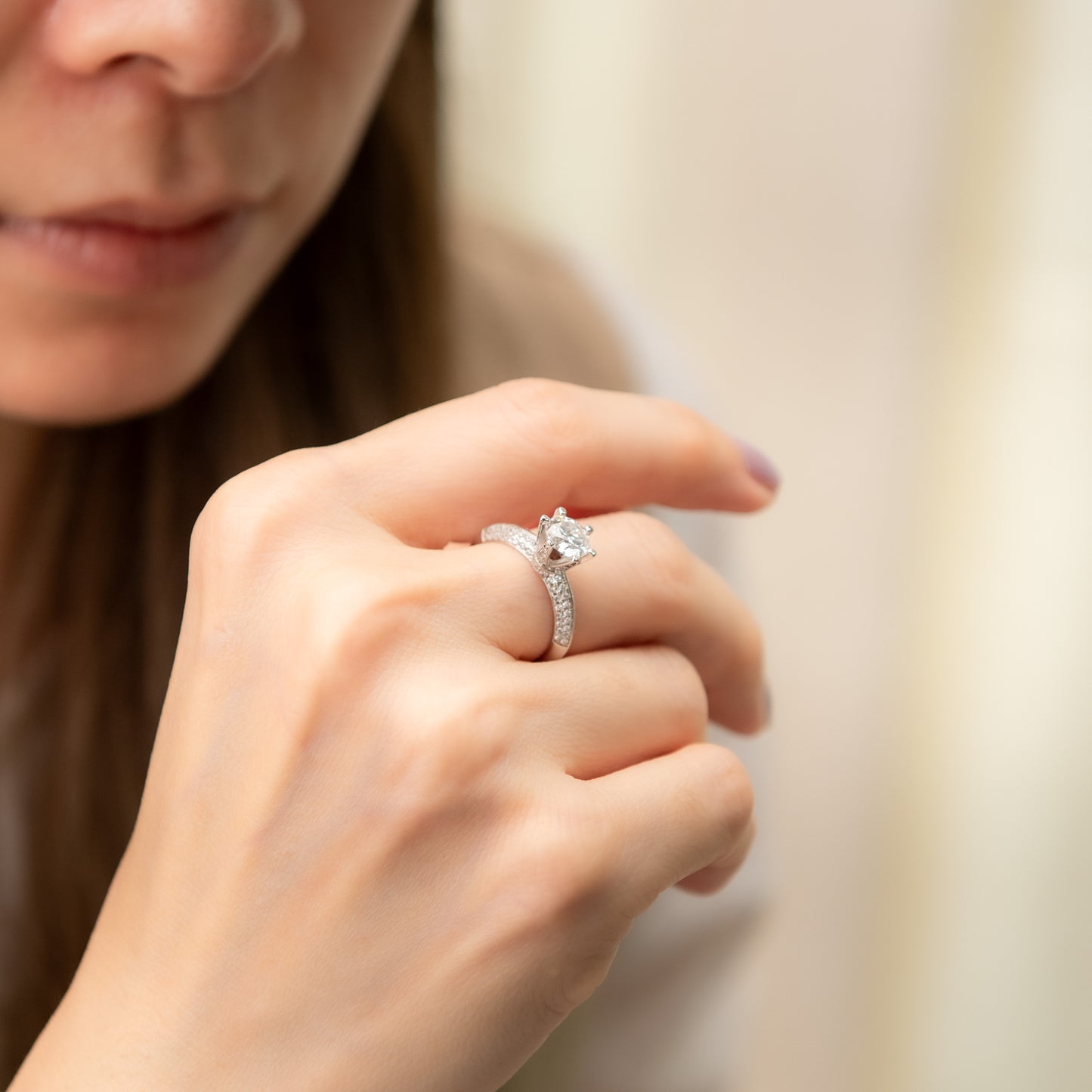 Close-up of a hand wearing a diamond ring with a blurred background