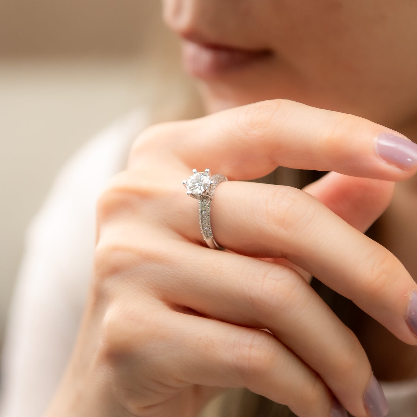 Close-up of a hand wearing a diamond ring with a blurred background
