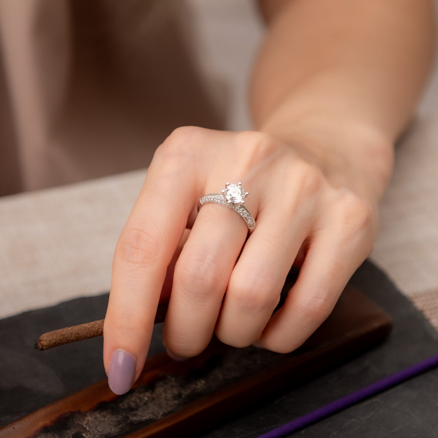 Hand wearing a diamond ring on a neutral background