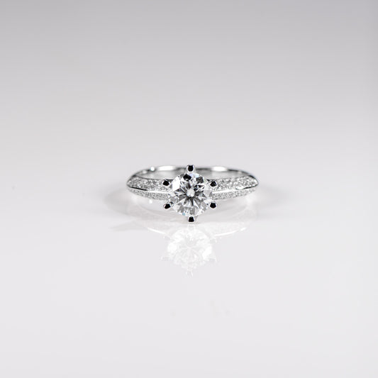 Silver ring with a central diamond and smaller stones on a light gray background