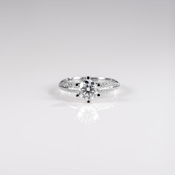 Silver ring with a central diamond and smaller stones on a light gray background