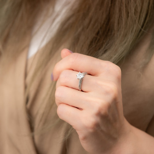 Close-up of a hand wearing a diamond ring with blurred hair in the background