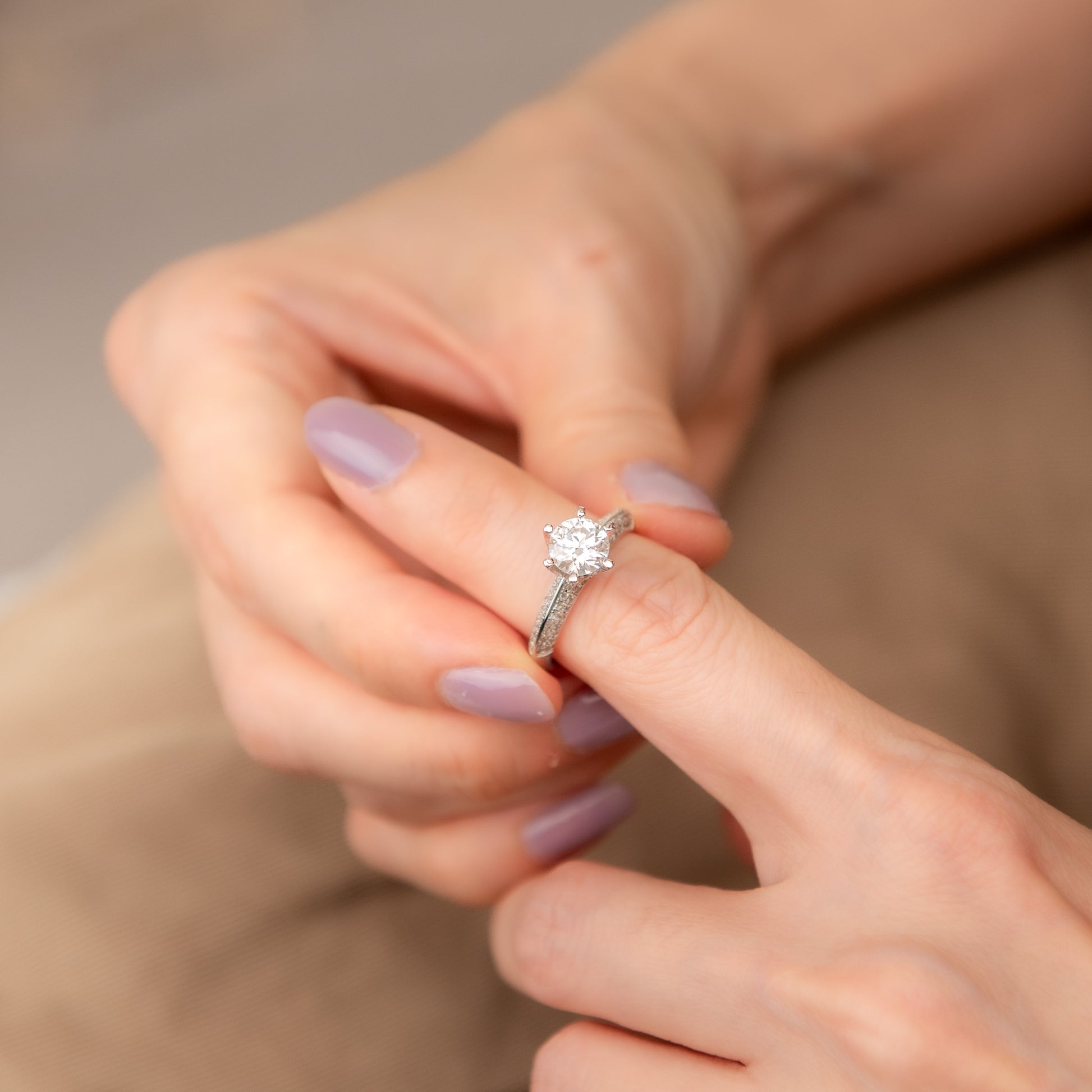 Close-up of a hand wearing a diamond ring with a soft focus background