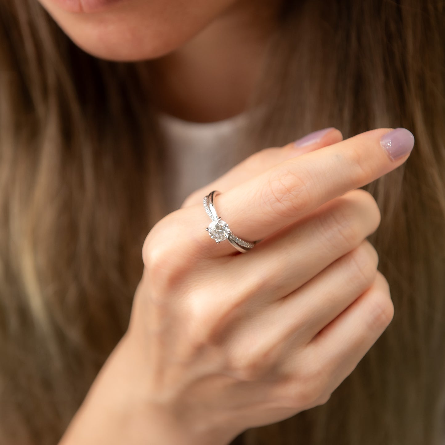 Close-up of a hand wearing a diamond ring with a blurred background