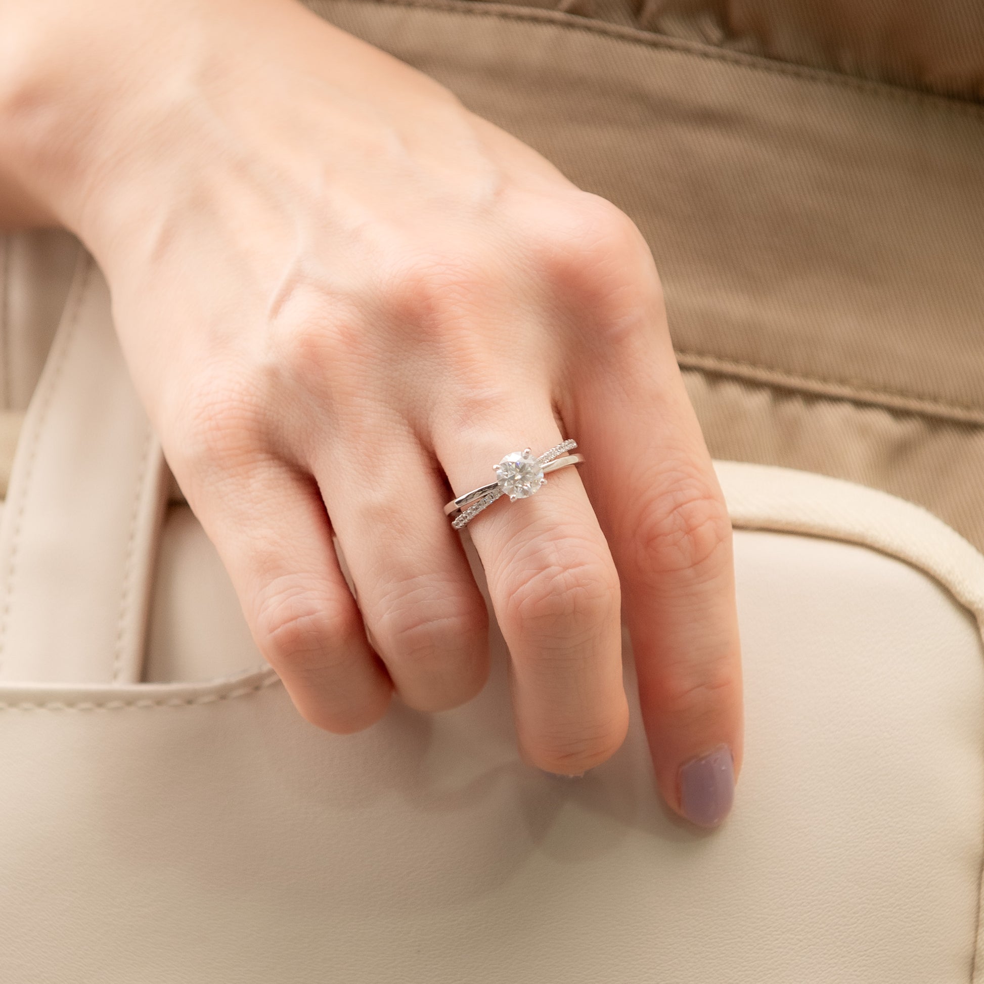 Close-up of a hand wearing two diamond rings on a beige background