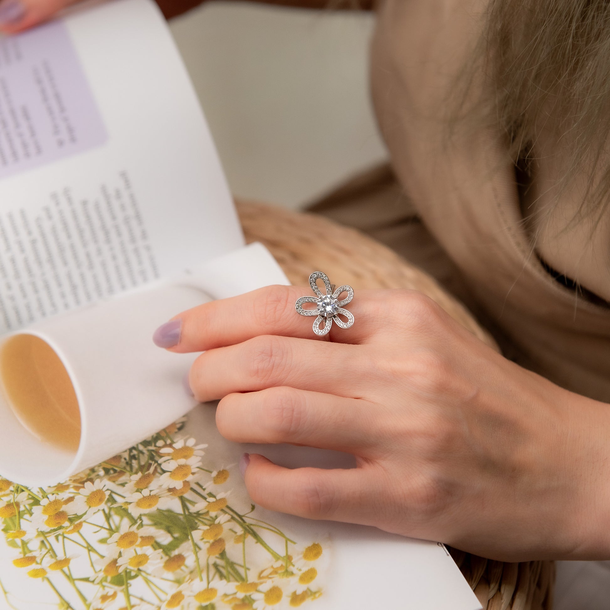 Person reading a book with a decorative ring on a floral-patterned surface