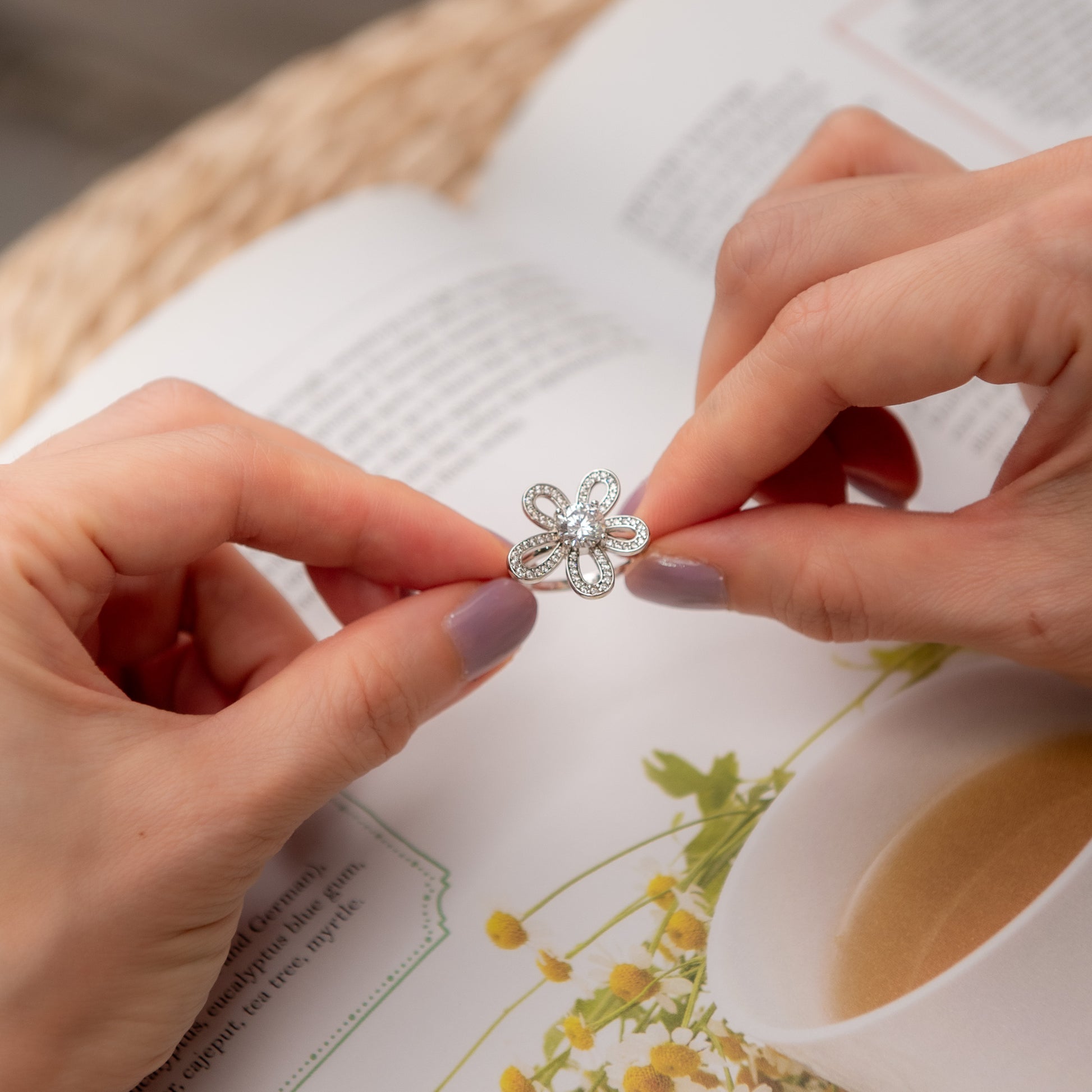 Person holding a silver flower-shaped earring with a blurred background