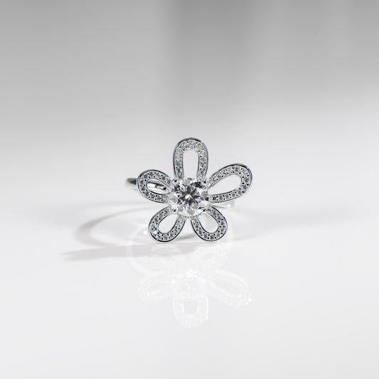 Silver flower-shaped ring with clear gemstone on a light gray background
