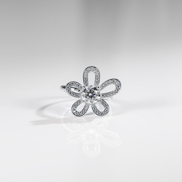 Silver flower-shaped ring with clear gemstone on a light gray background