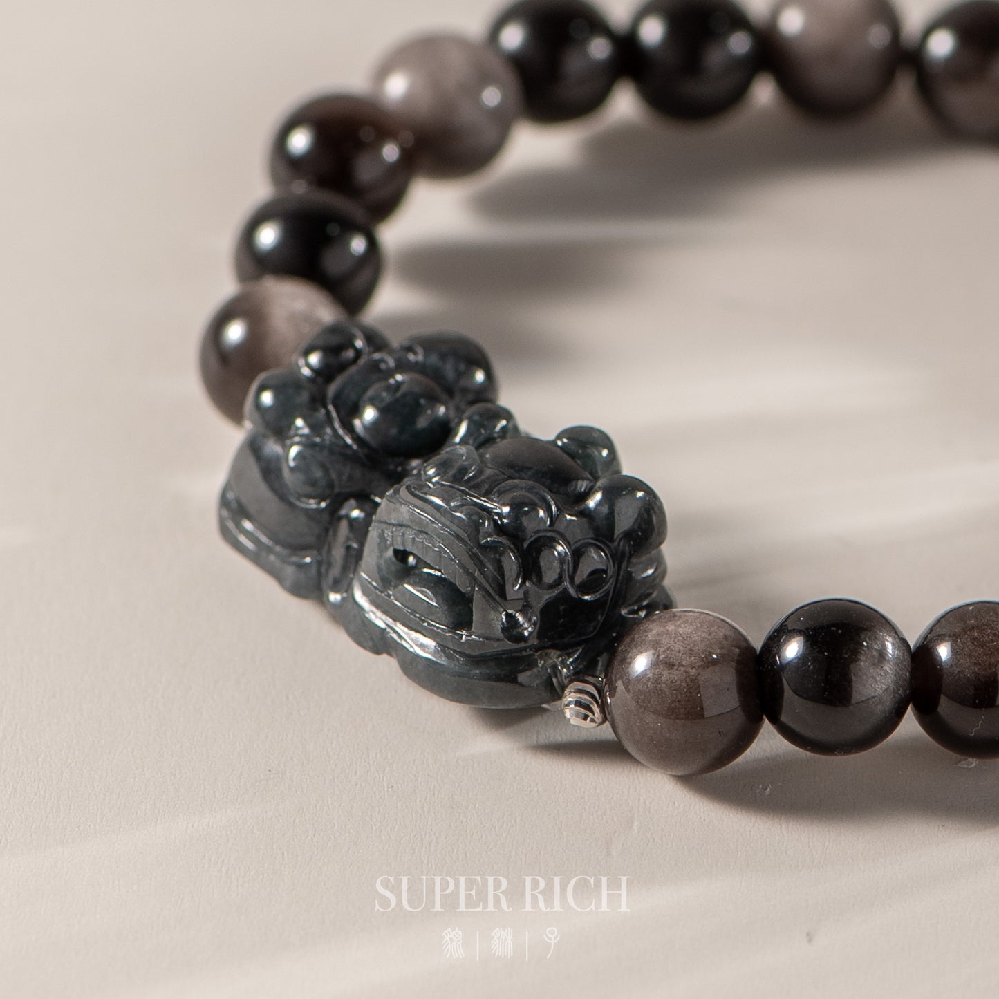 Black beaded bracelet with a detailed black stone clasp on a beige background