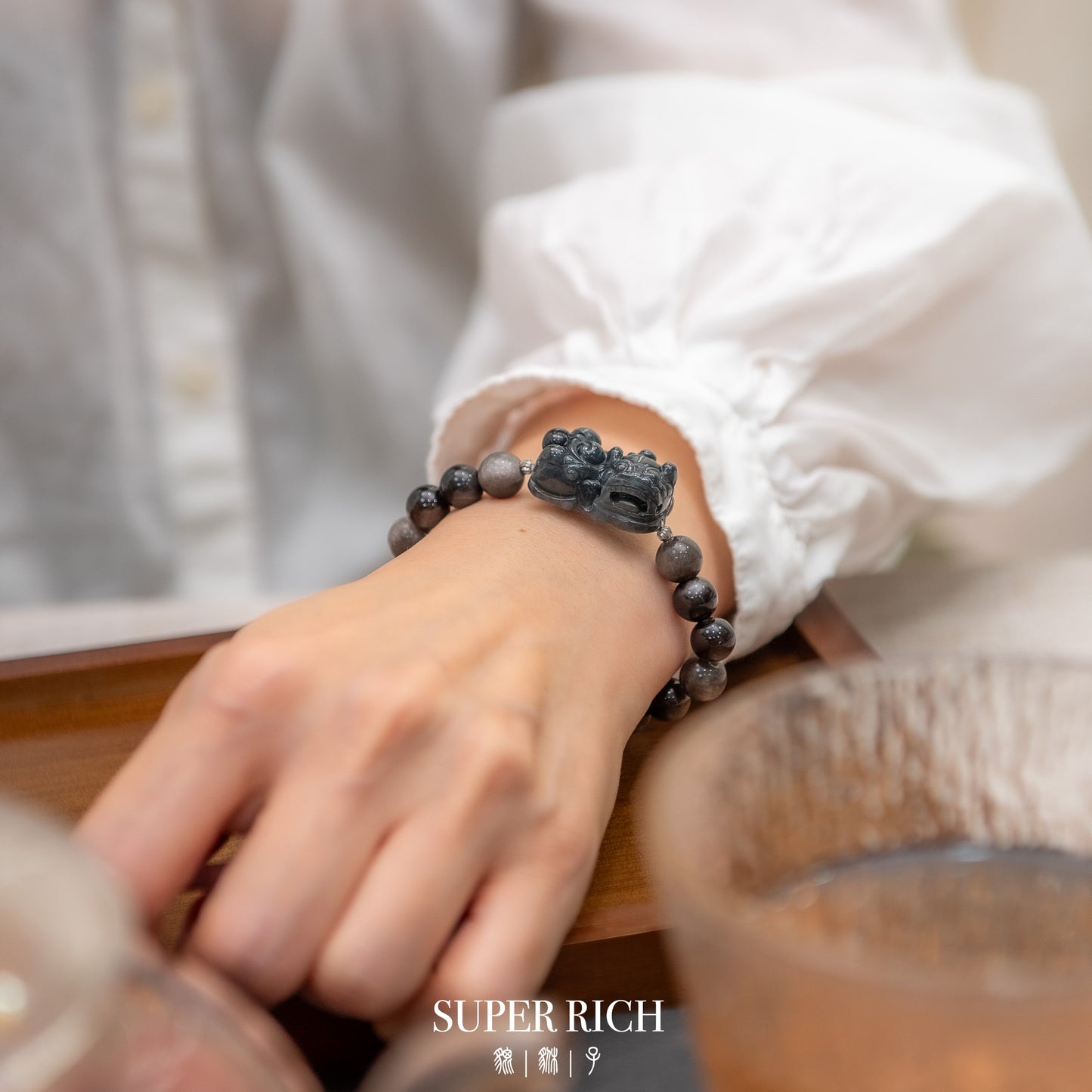 Person wearing a black beaded bracelet with a dragon design on a blurred background