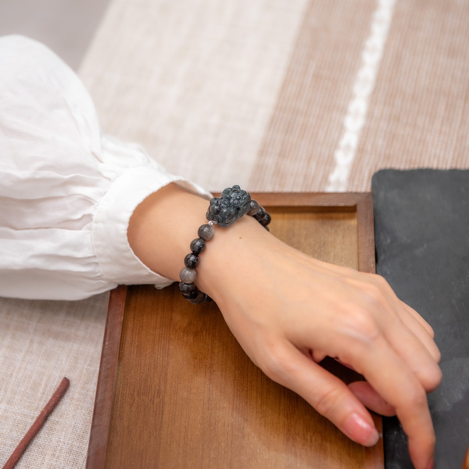 Hand wearing a bracelet with a stone design on a wooden surface