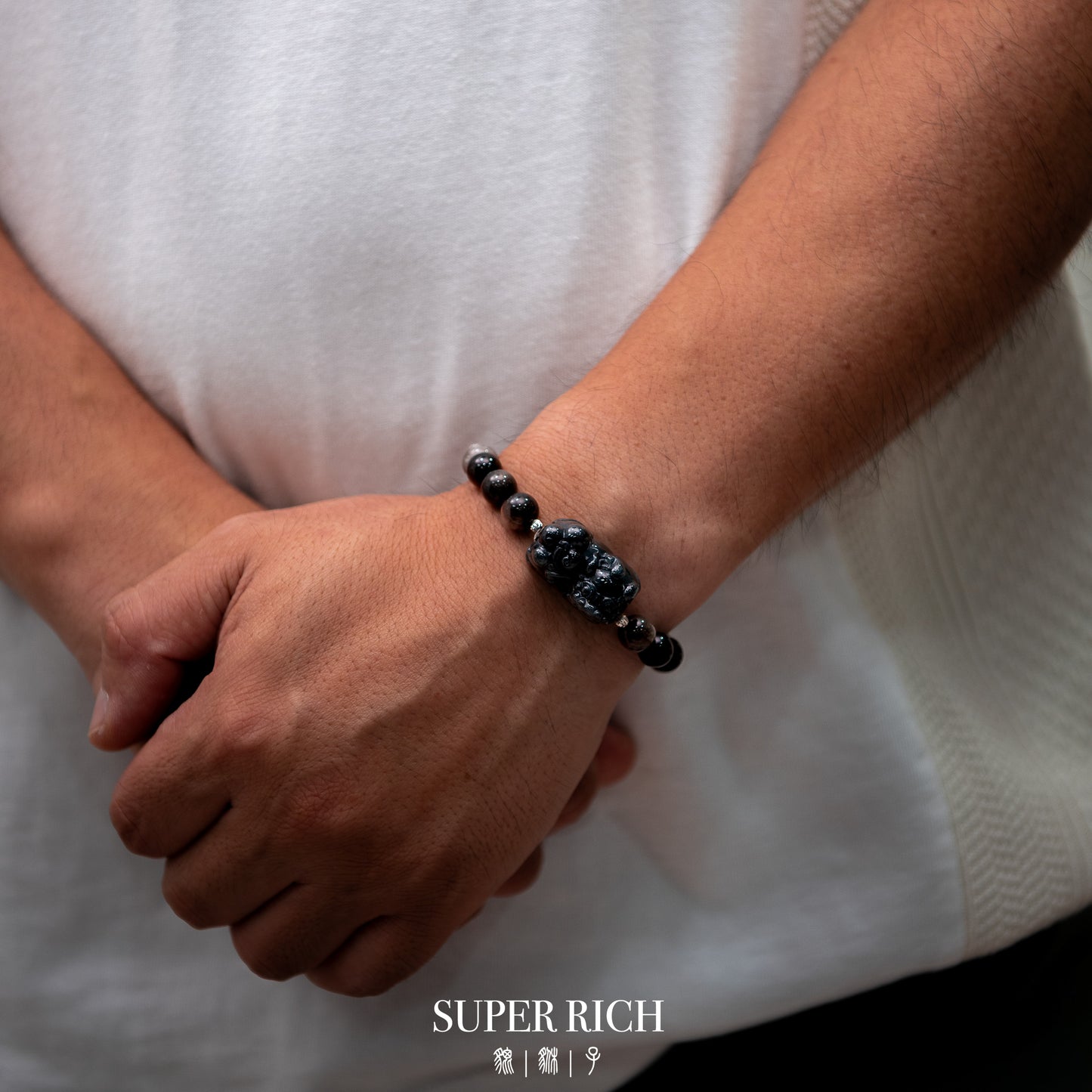 Man wearing black jade Pixiu bracelet with obsidian beads, minimalist luxury jewelry styled on wrist with calm modern aesthetic