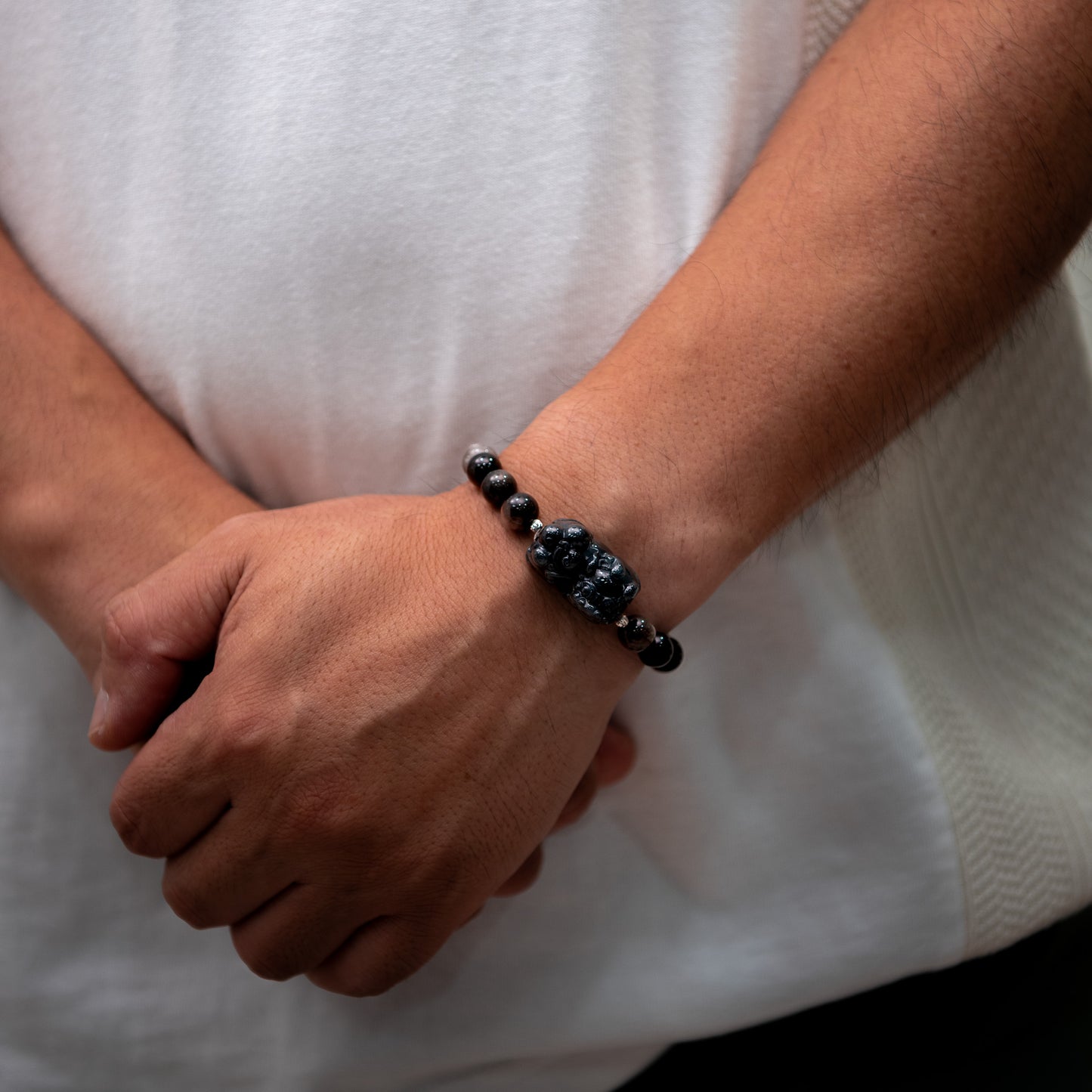 Person wearing a black beaded bracelet on a white background