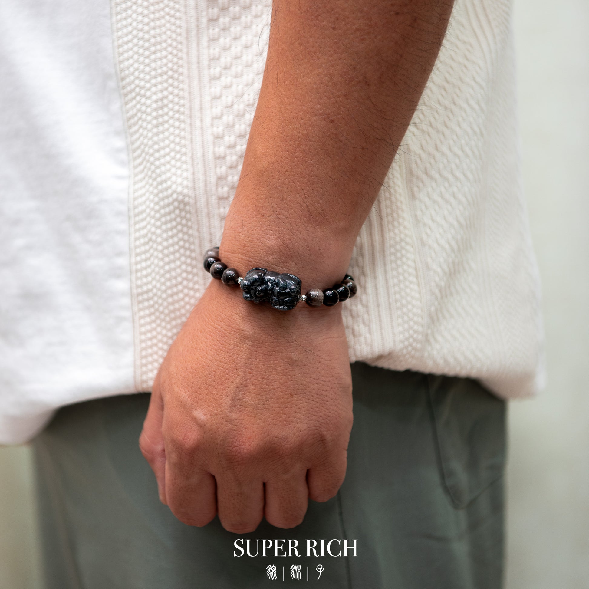 Person wearing a beaded bracelet on a plain background with 'SUPER RICH' branding.
