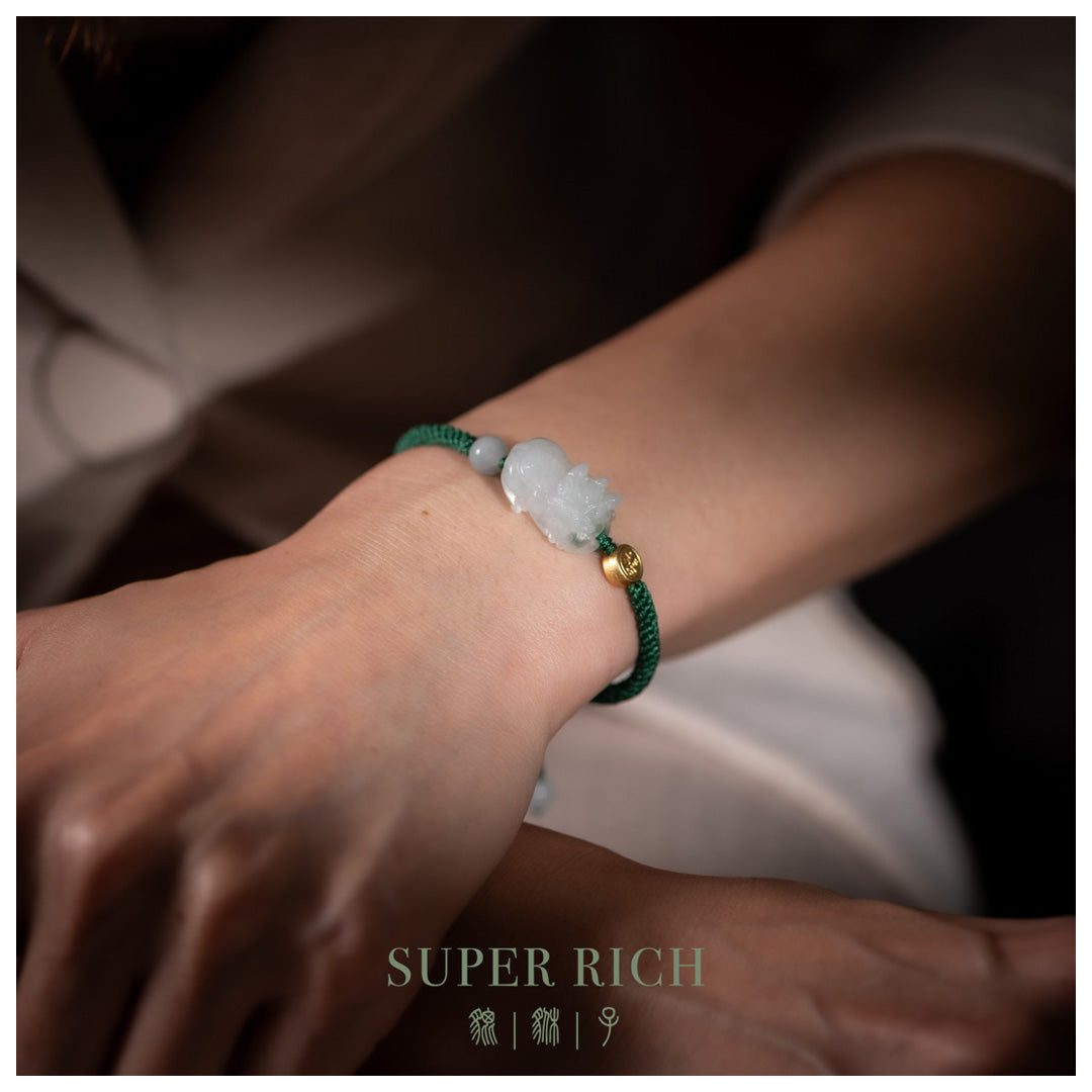 Close-up of a wrist wearing a green bracelet with a white stone, brand 'SUPER RICH' visible.