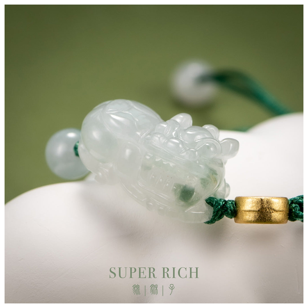 Green jade pendant with gold accent on a white surface, labeled 'SUPER RICH'.